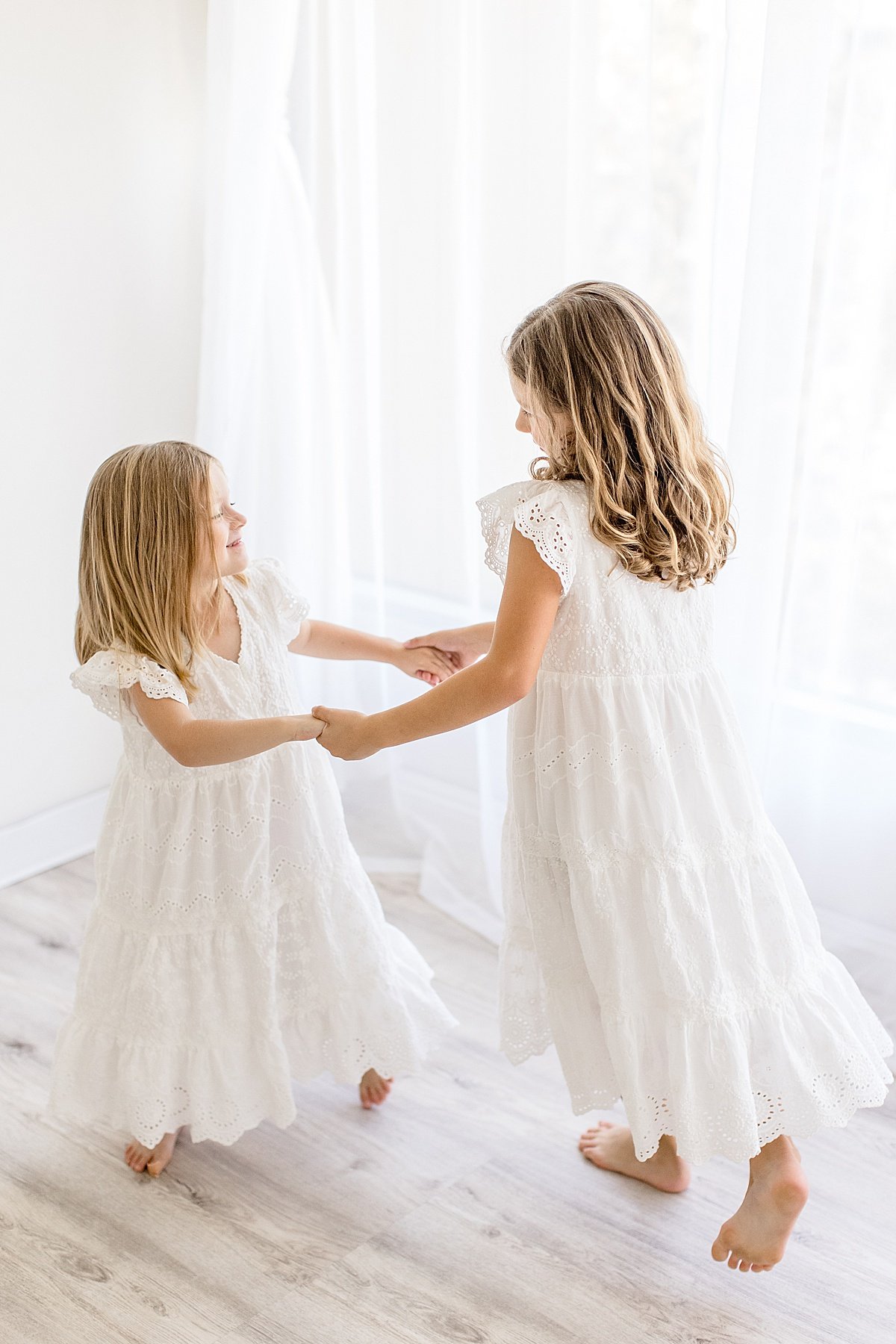 Two sisters playing together holding hands during portrait session at Newport Beach photography studio with Ambre Williams