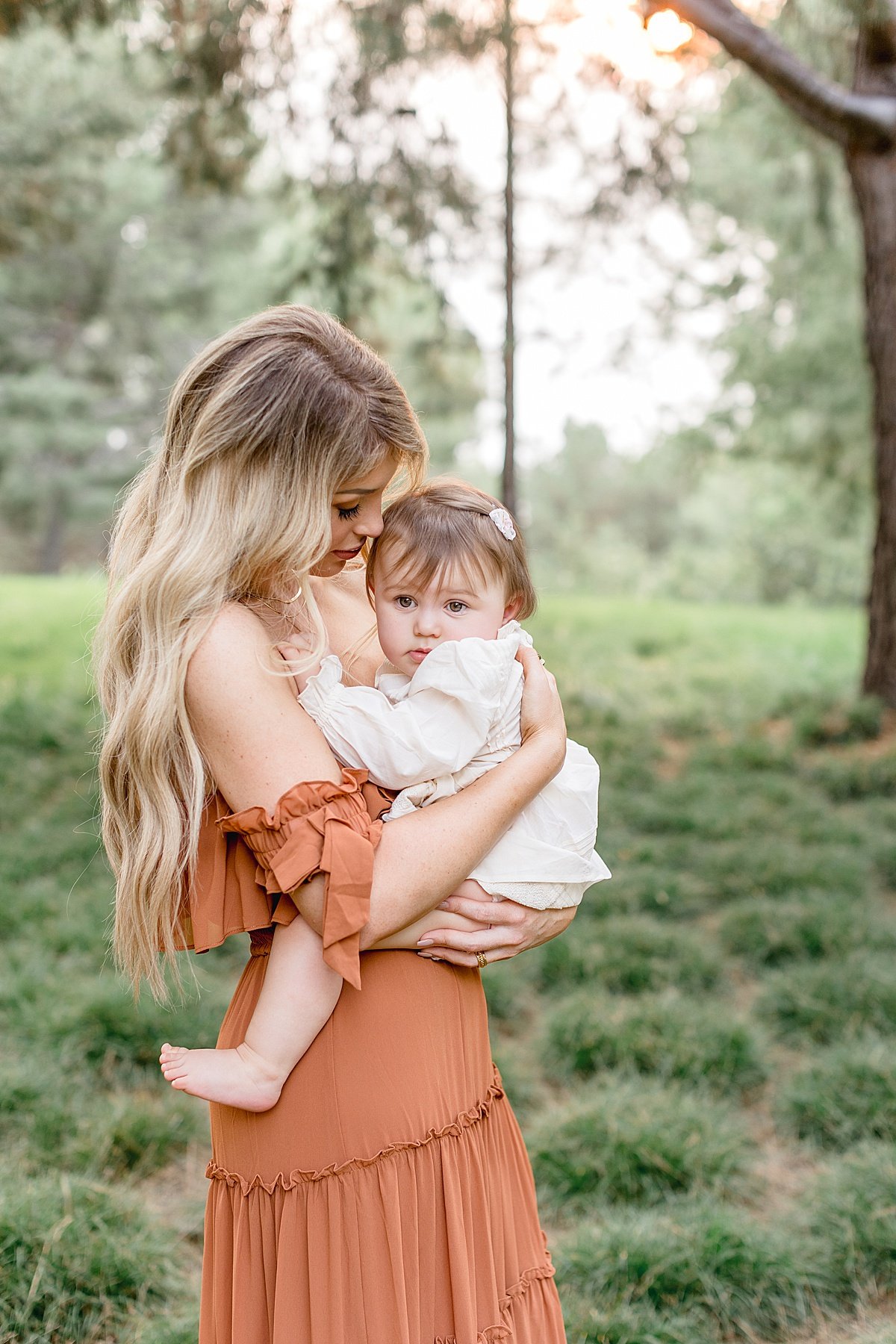 Beautiful Mama in orange holding young daughter during fall portrait session with Ambre Williams Photography in Newport Beach Lake Forest California