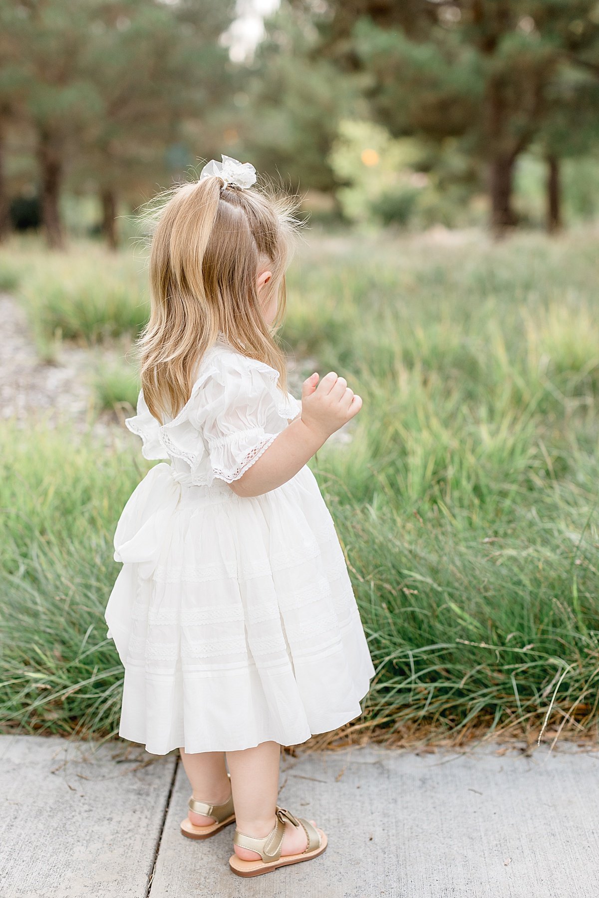 Candid portrait of small daughter in white fluffy dress on sidewalk in Lake Forest California with Photographer Ambre Williams