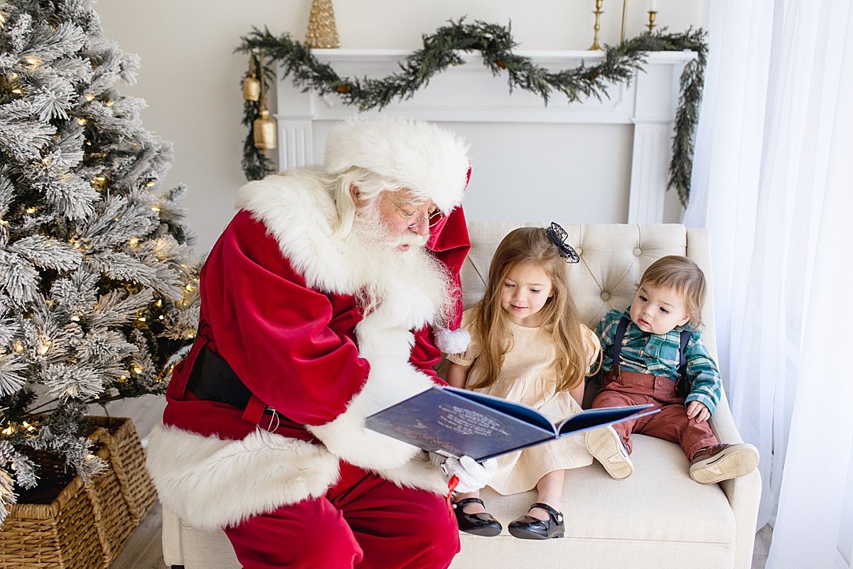 Candid photo of Santa reading children a Christmas story during Santa's Magical Experience in Newport Beach studio with Ambre Williams Photography