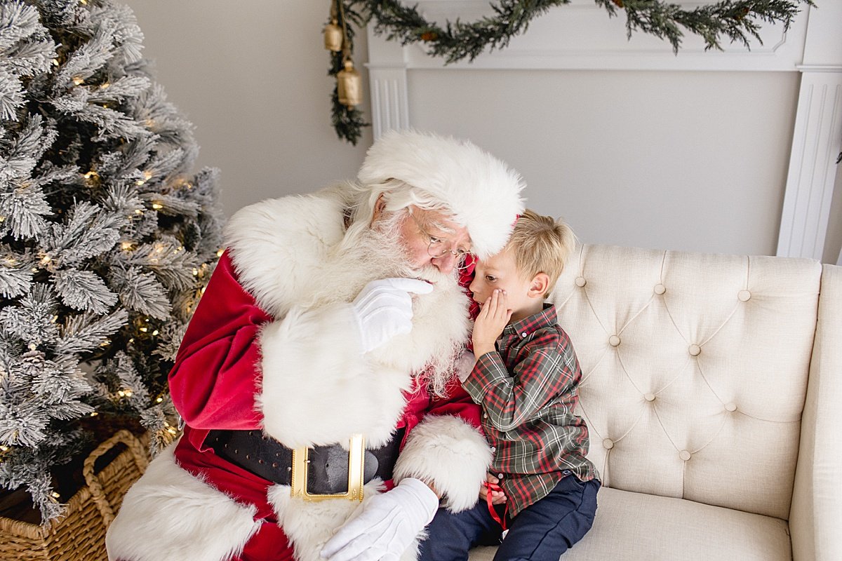Toddler telling Santa what he wants for Christmas during Santa's Magical Experience with Ambre Williams Photography in Newport Beach studio
