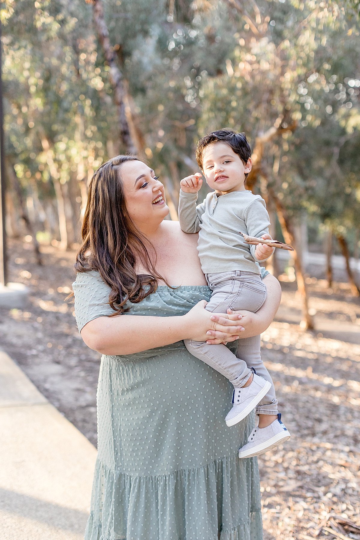 Mom and Son smiling at each other. Candid portrait during fall family portrait session with Ambre Williams Photography in California Forest