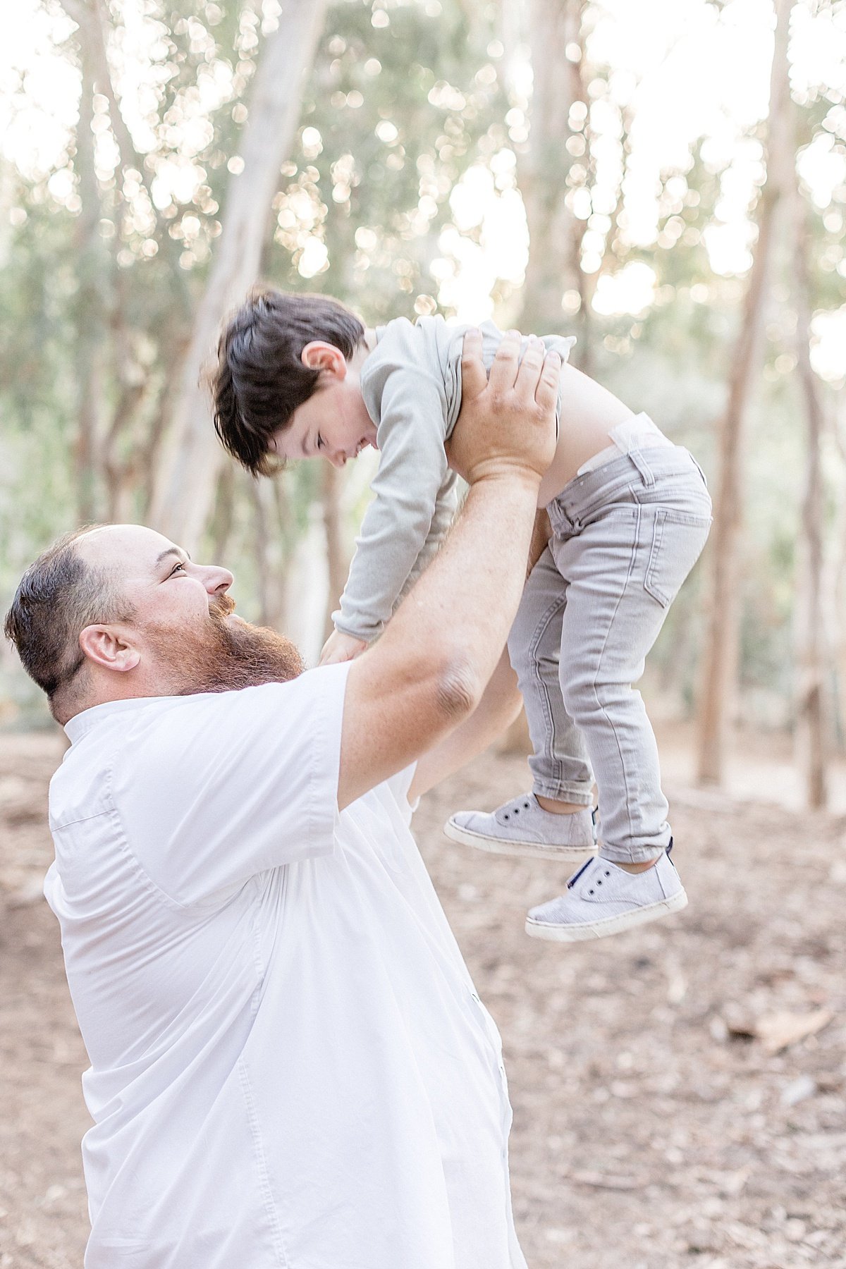 Dad playing with Son during portrait session outdoor fall forest session with Ambre Williams Photography