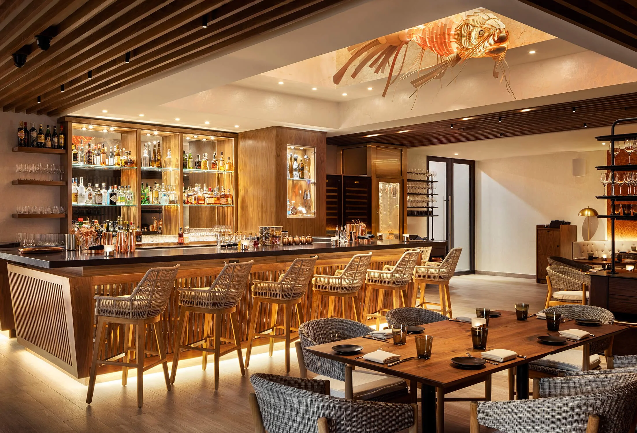 Upscale restaurant bar with lobster ceiling sculpture, warm wood tones and amber lighting, hospitality photography by Brian Berkowitz Photography