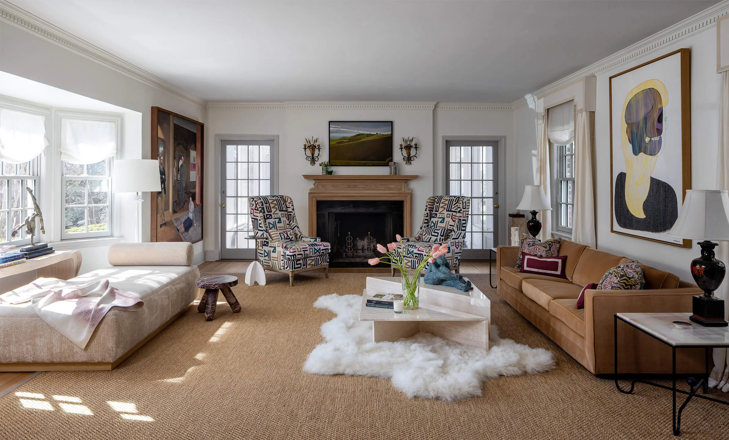 living room with patterned accent chairs flanking a wood mantle fireplace, shag rug, mixed art collection, and large-scale portrait painting, photographed by Brian Berkowitz Photography on Long Island