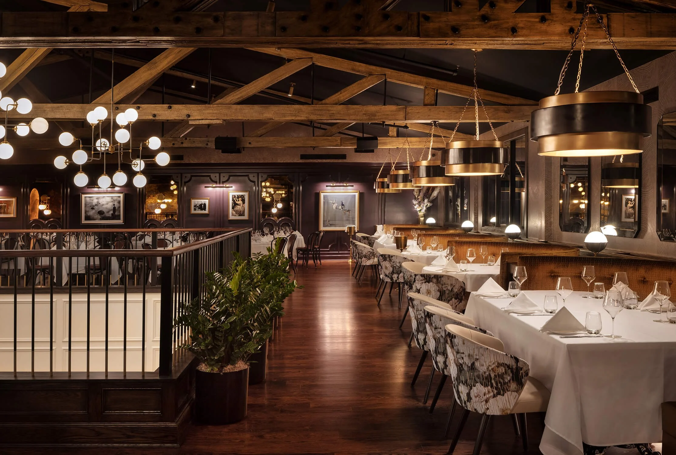 Elegant restaurant dining room with exposed wood beams, globe pendant lights and white tablecloths, hospitality photography by Brian Berkowitz Photography
