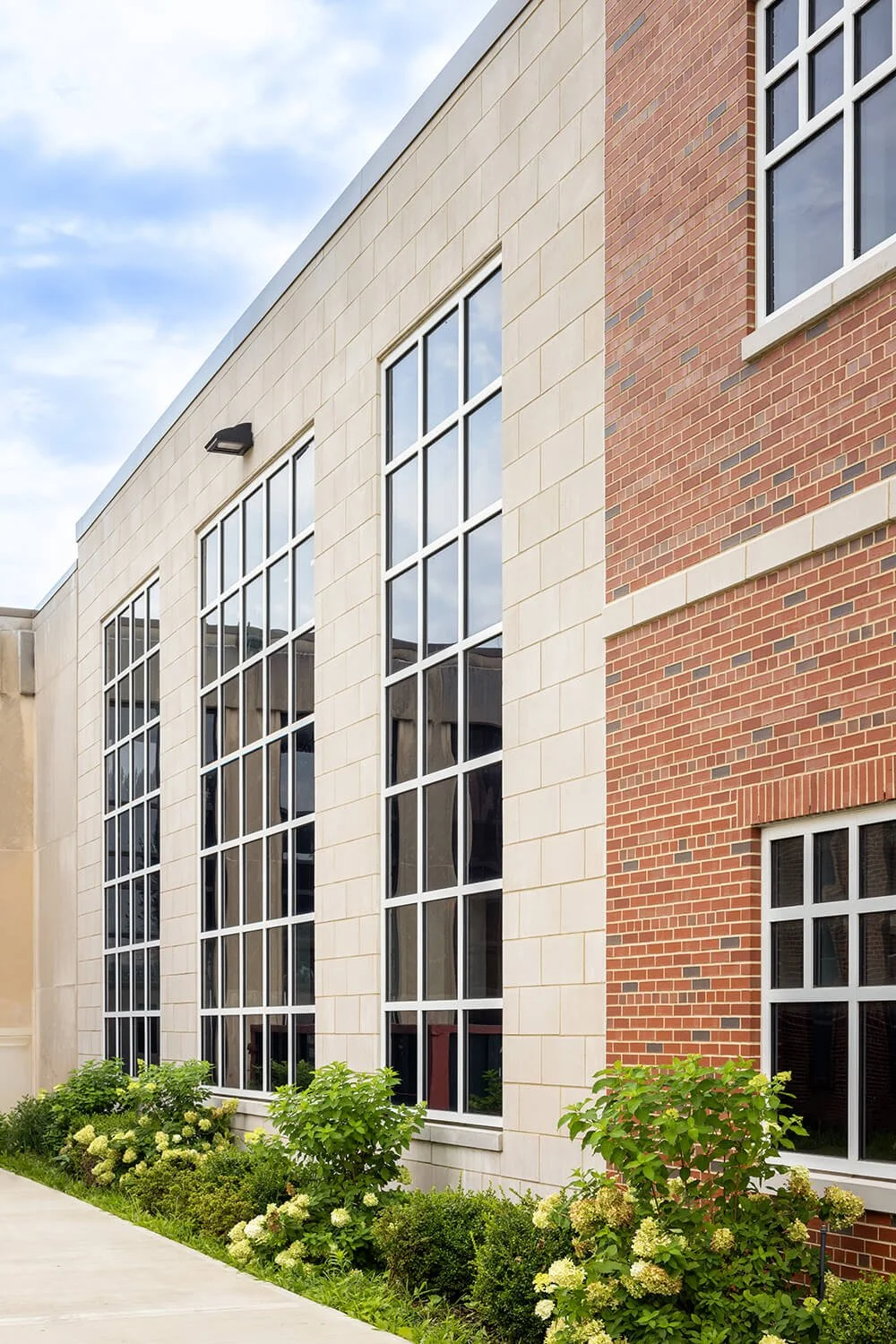School exterior with large glass curtain wall facade against brick architecture and landscaping, Campbell Cassetta Architects, Brian Berkowitz Photography