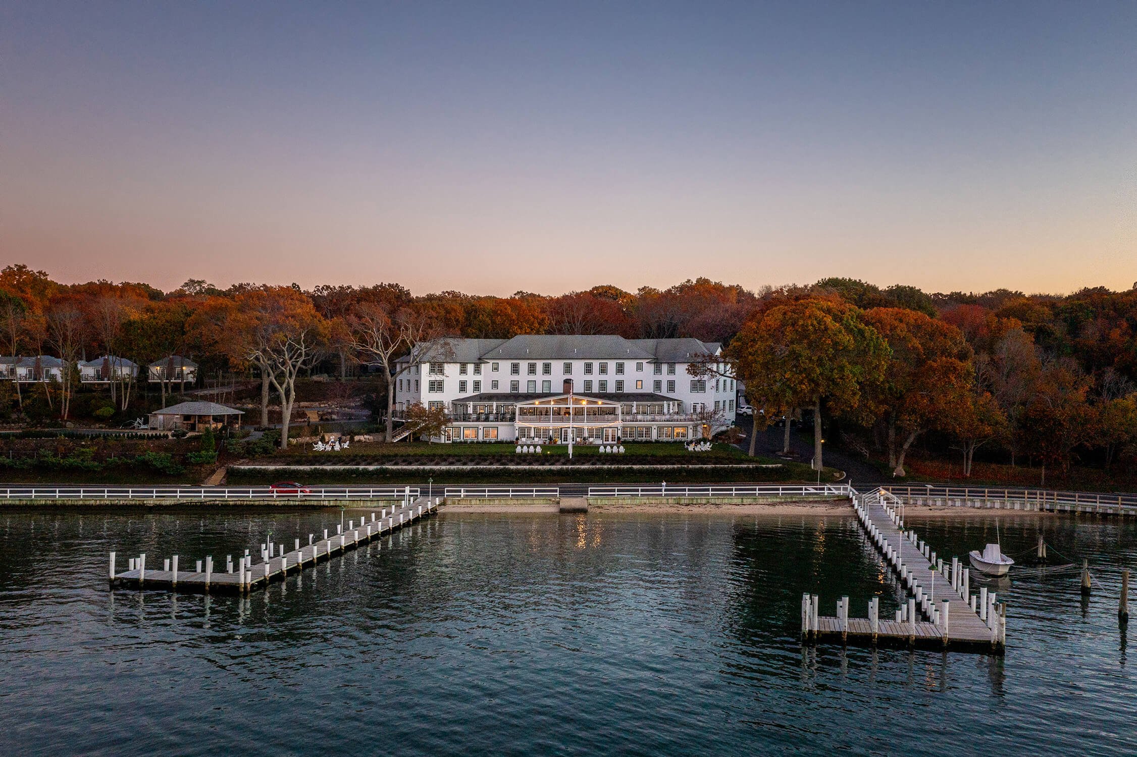 Luxury waterfront resort, Pridwin Hotel,  at dusk with fall foliage and dock, hospitality architectural photography by Brian Berkowitz Photography Long Island