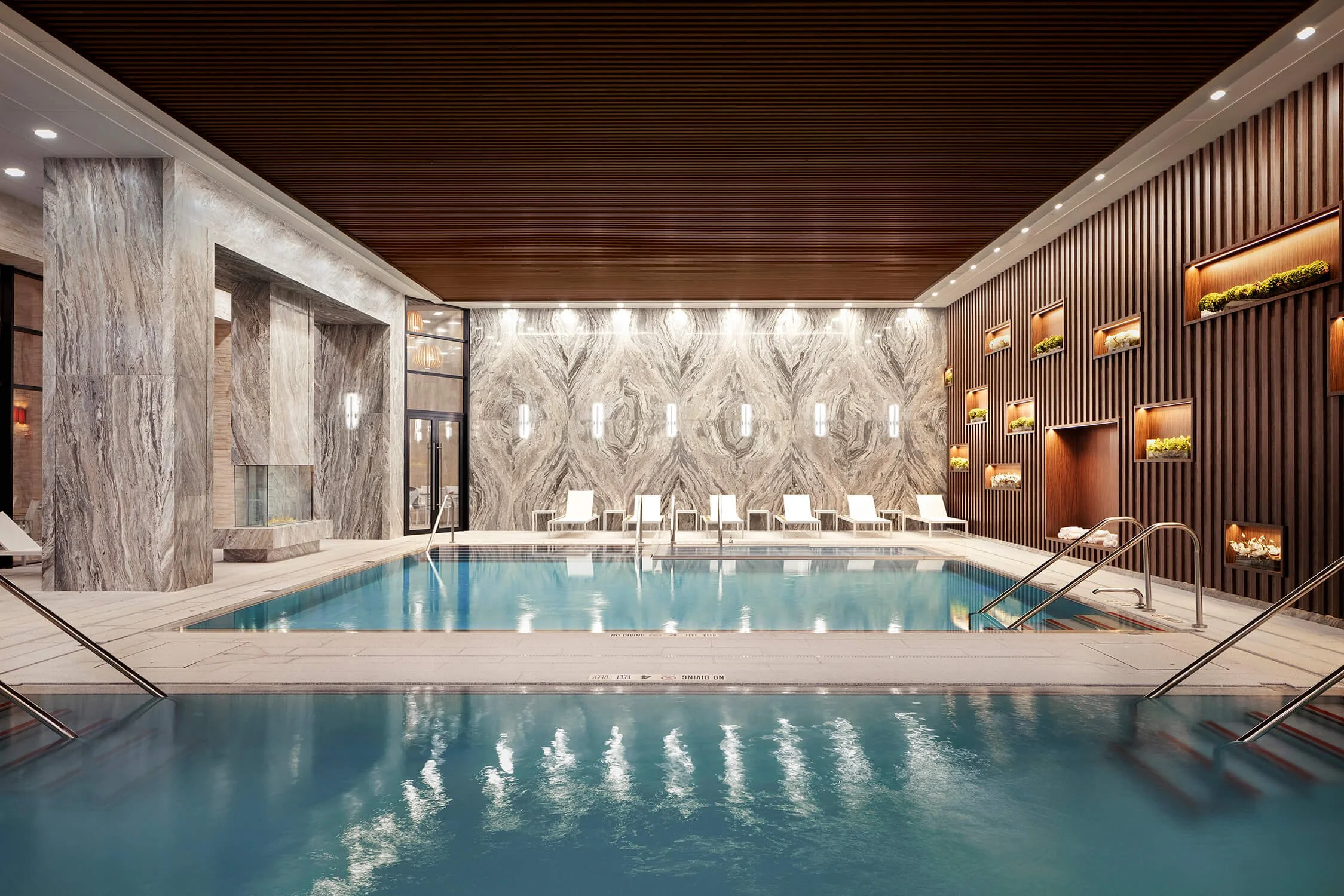 Luxury indoor pool with marble walls and wood slat ceiling, health and wellness architecture photography
