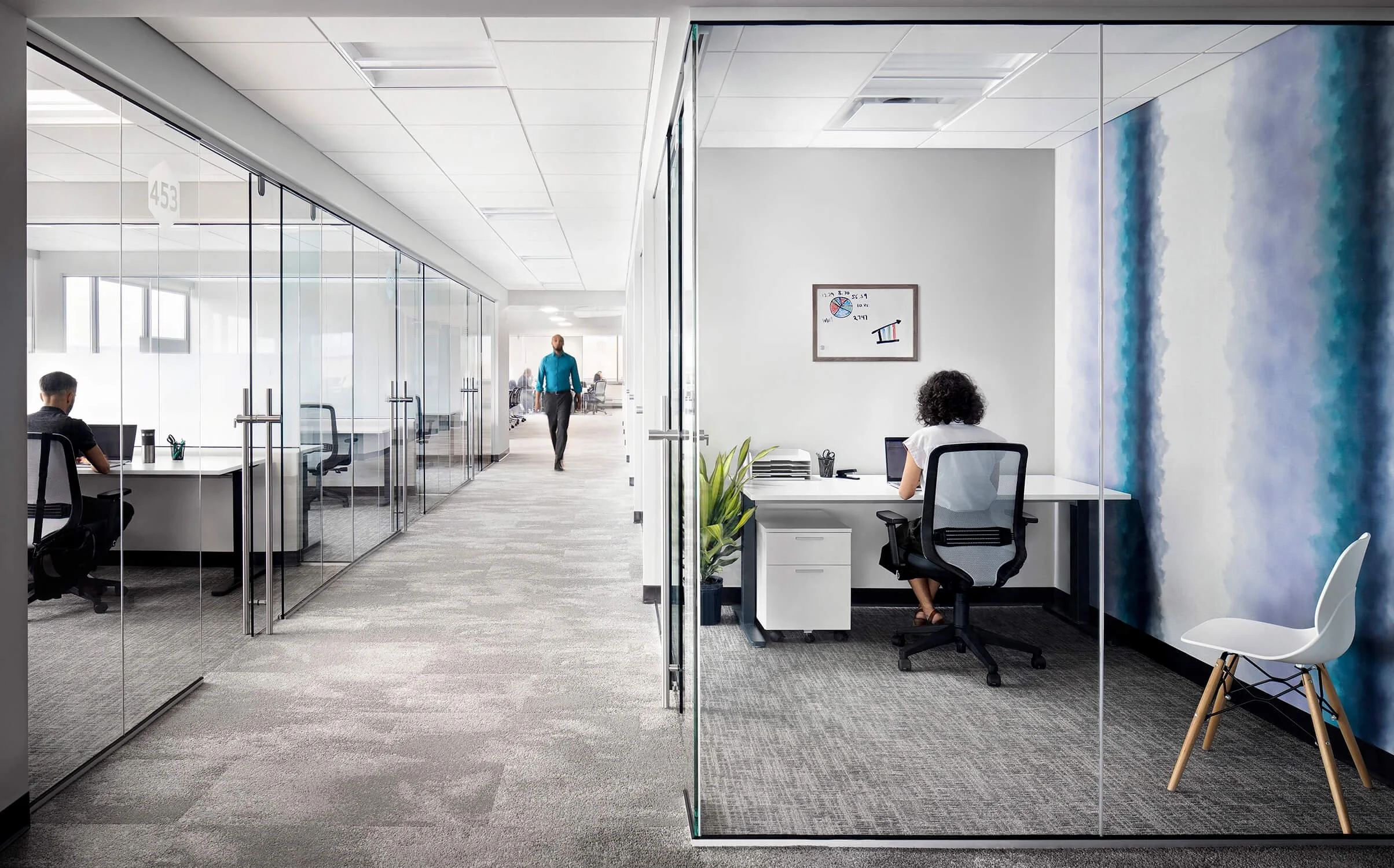 Corporate office glass corridor with reflection-free shooting, layered depth and people at workstations, architectural photography by Brian Berkowitz Photography New York