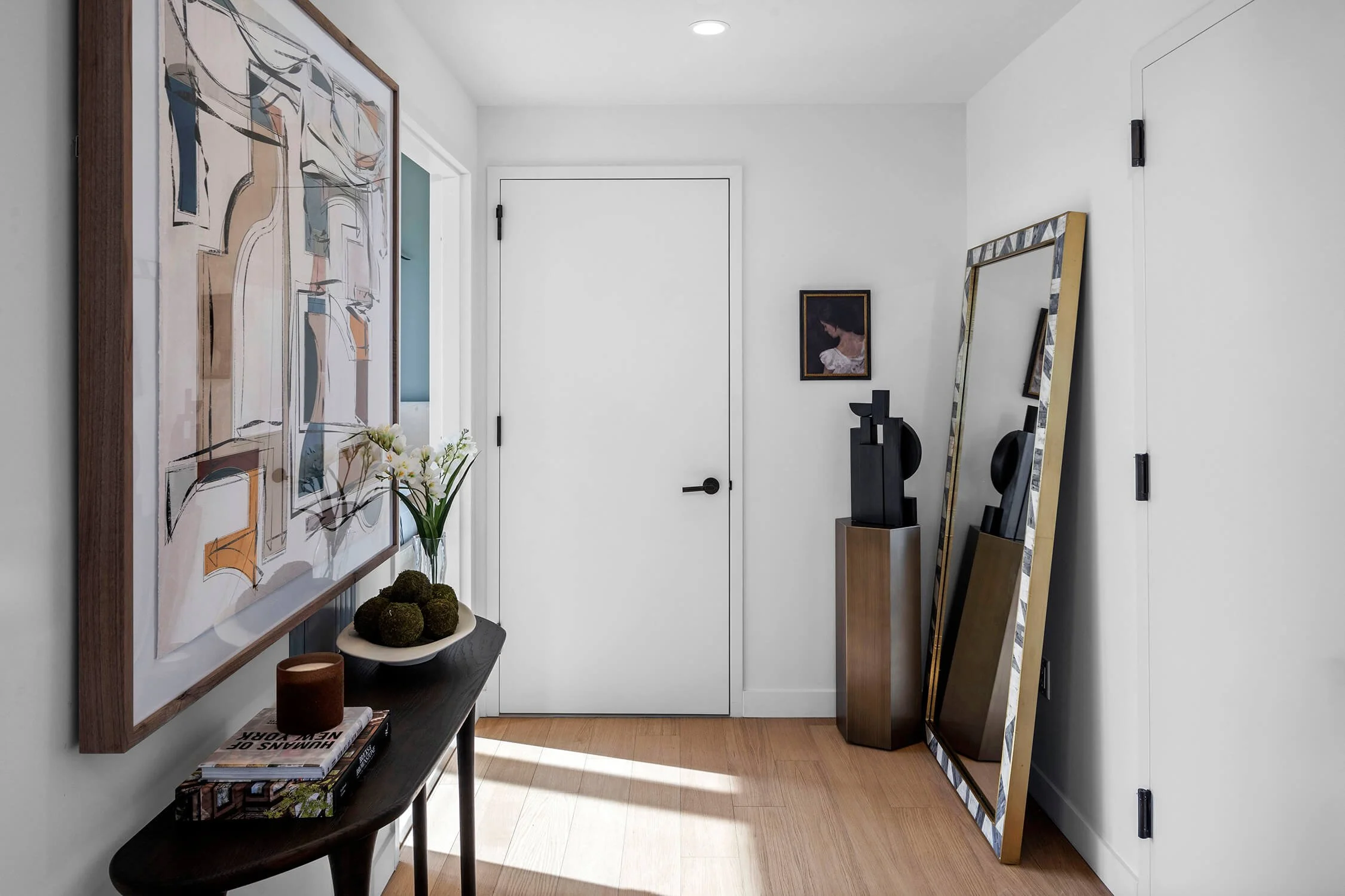 Modern entryway in Brooklyn penthouse with abstract artwork, console table, and decorative mirror.