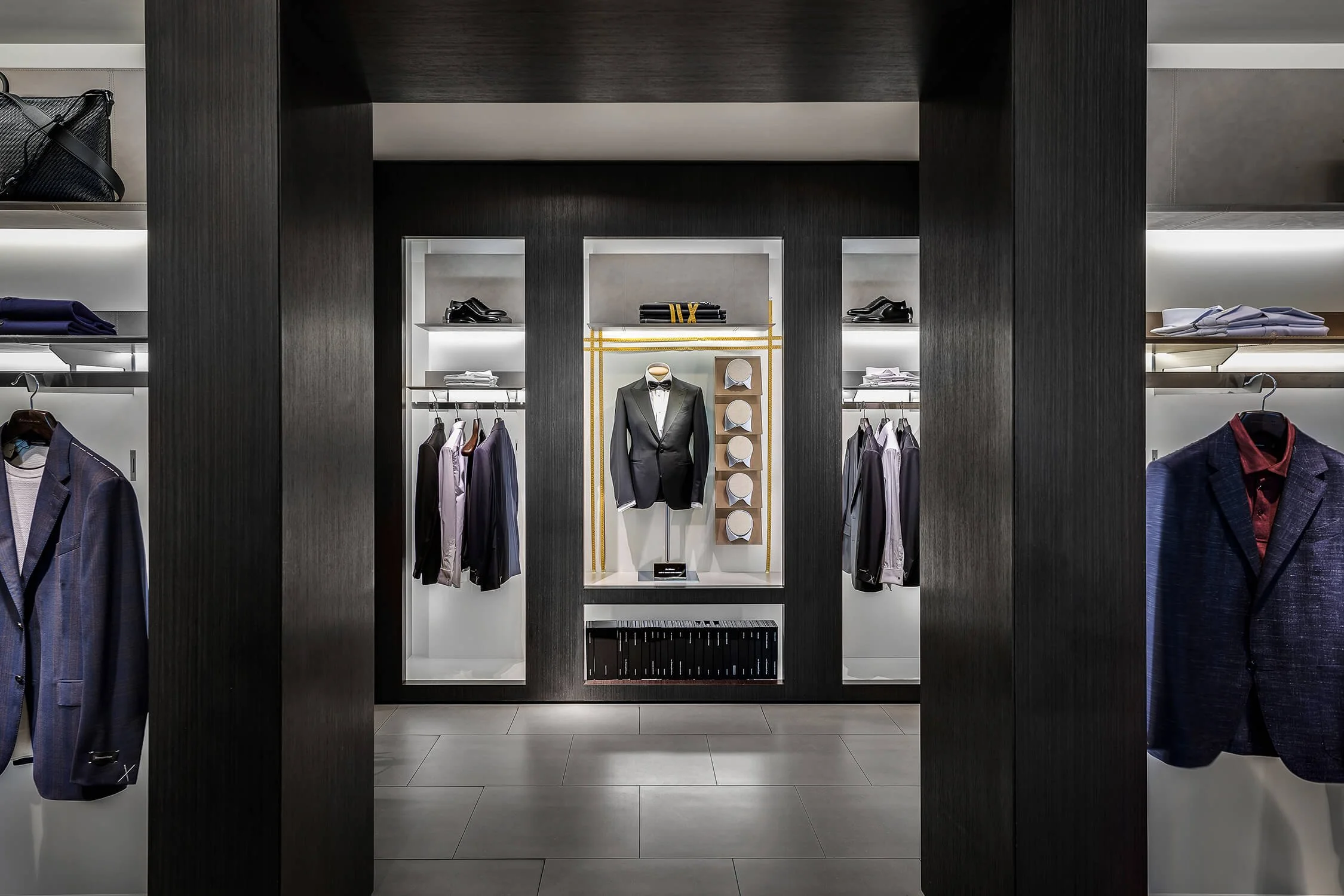 High end menswear retail store interior with dark wood millwork and display cases, luxury retail photography