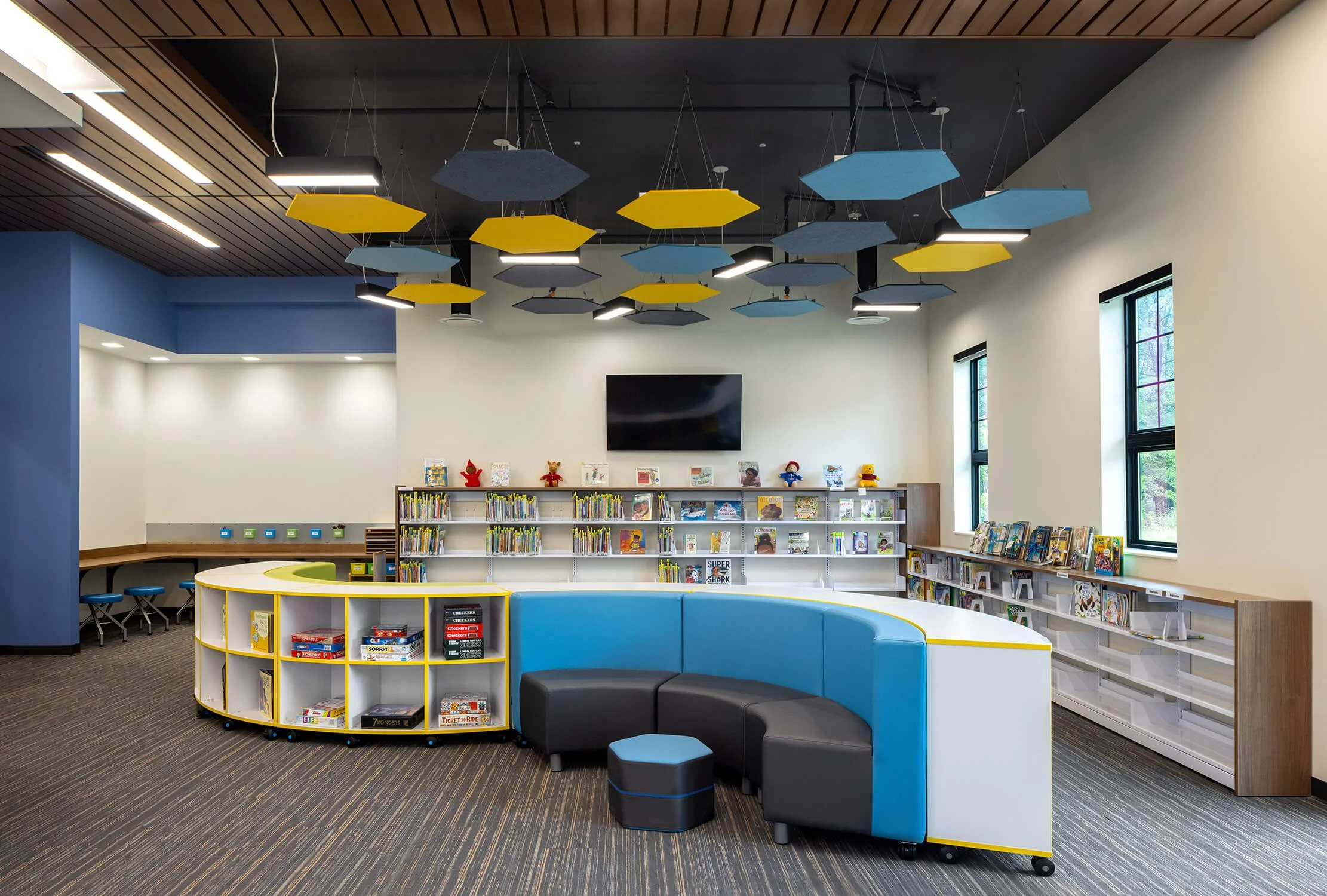 Children's library with circular bookshelf unit, blue curved seating and acoustic ceiling panels, education photography by Brian Berkowitz Photography