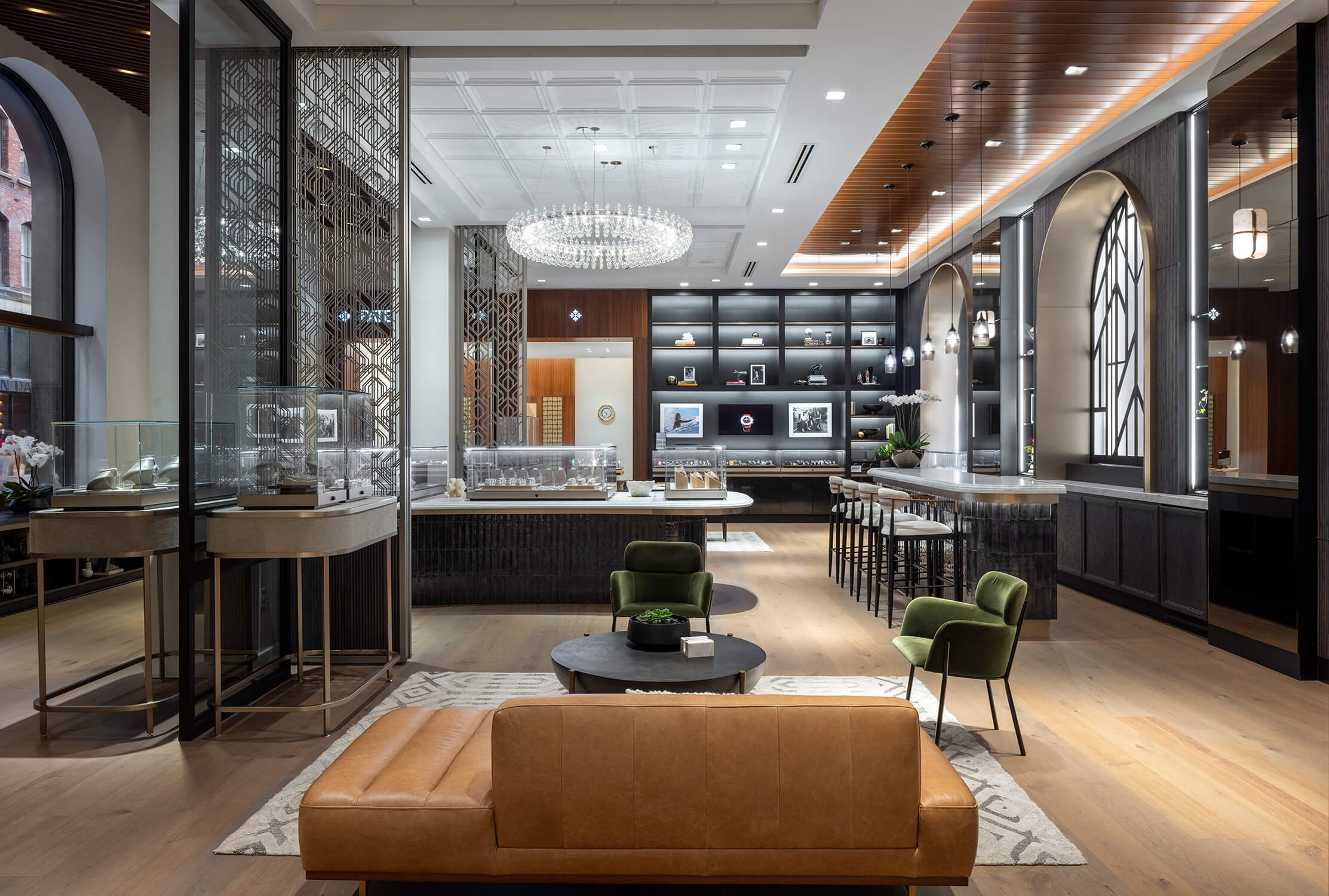 Elegant jewelry showroom with crystal chandelier, mixed material ceiling, modern display counters, and plush seating in a warm-toned, contemporary space