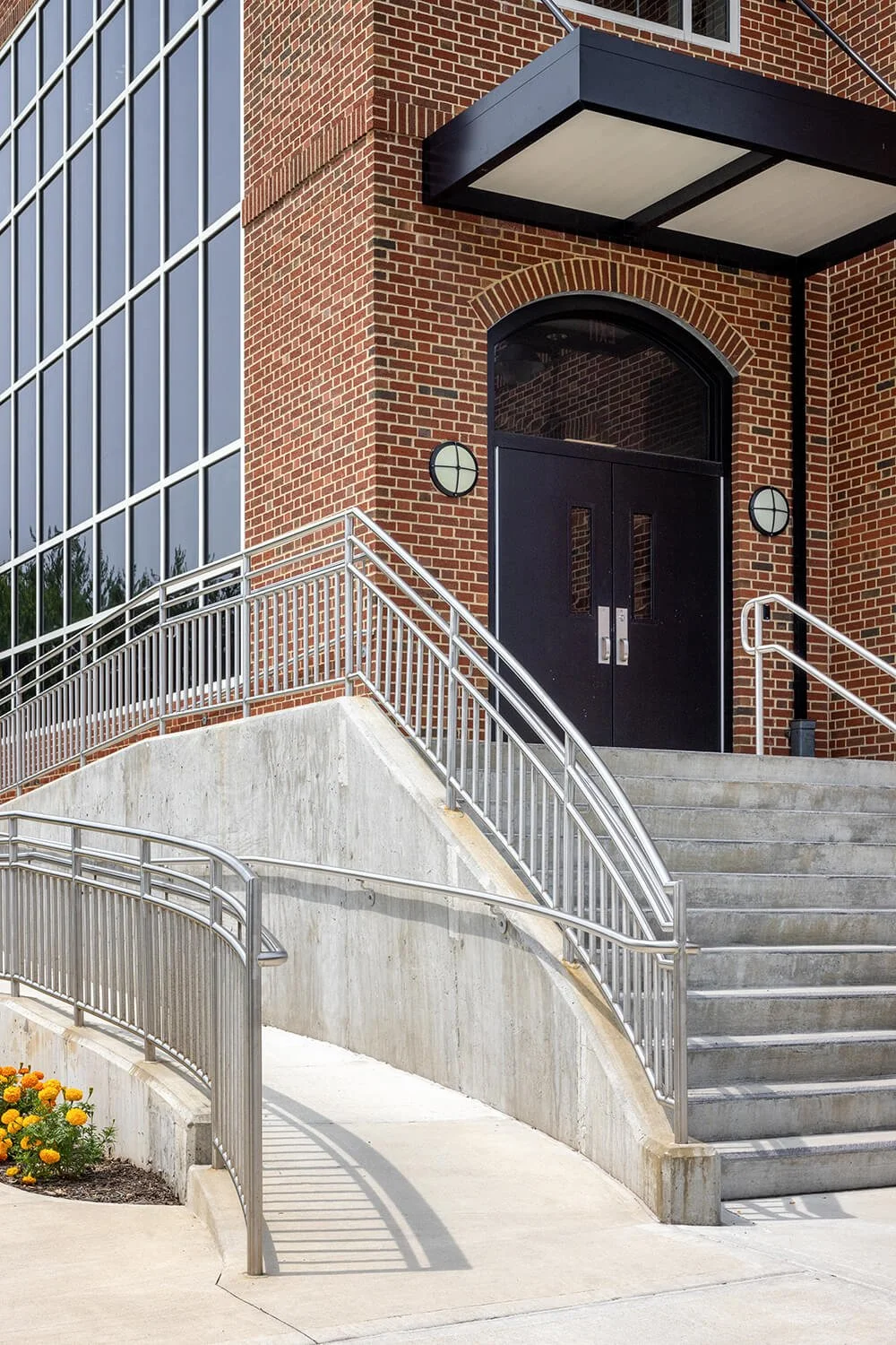 School entrance with curved staircase, brick arch and modern glass canopy, Campbell Cassetta Architects, Brian Berkowitz Photography Long Island