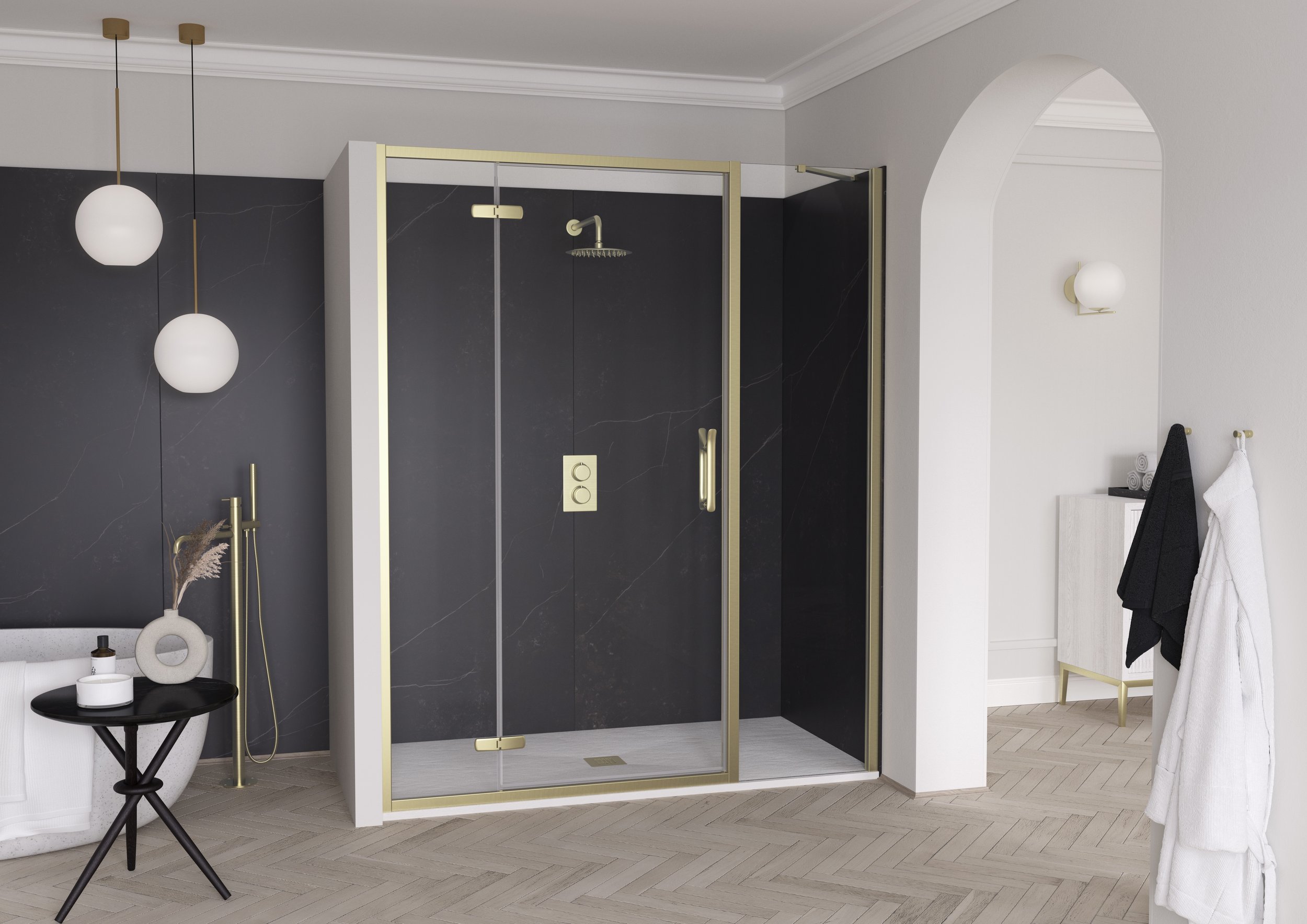 Modern bathroom with a glass shower enclosure with gold accents, black and white decor, white walls, a black side table with accessories, and a white chair with towels draped over it.