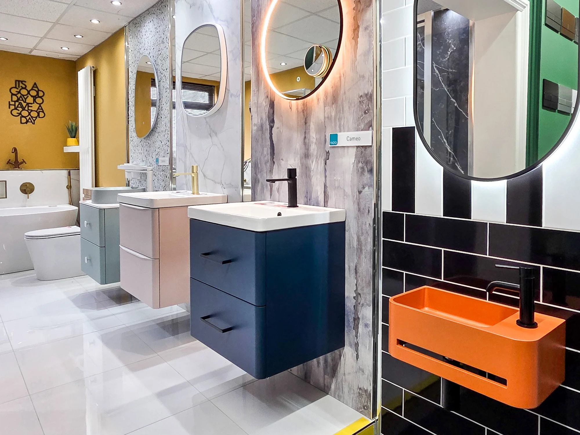 Display of bathroom sinks, mirrors, and fixtures in a showroom with colorful decor and modern design.