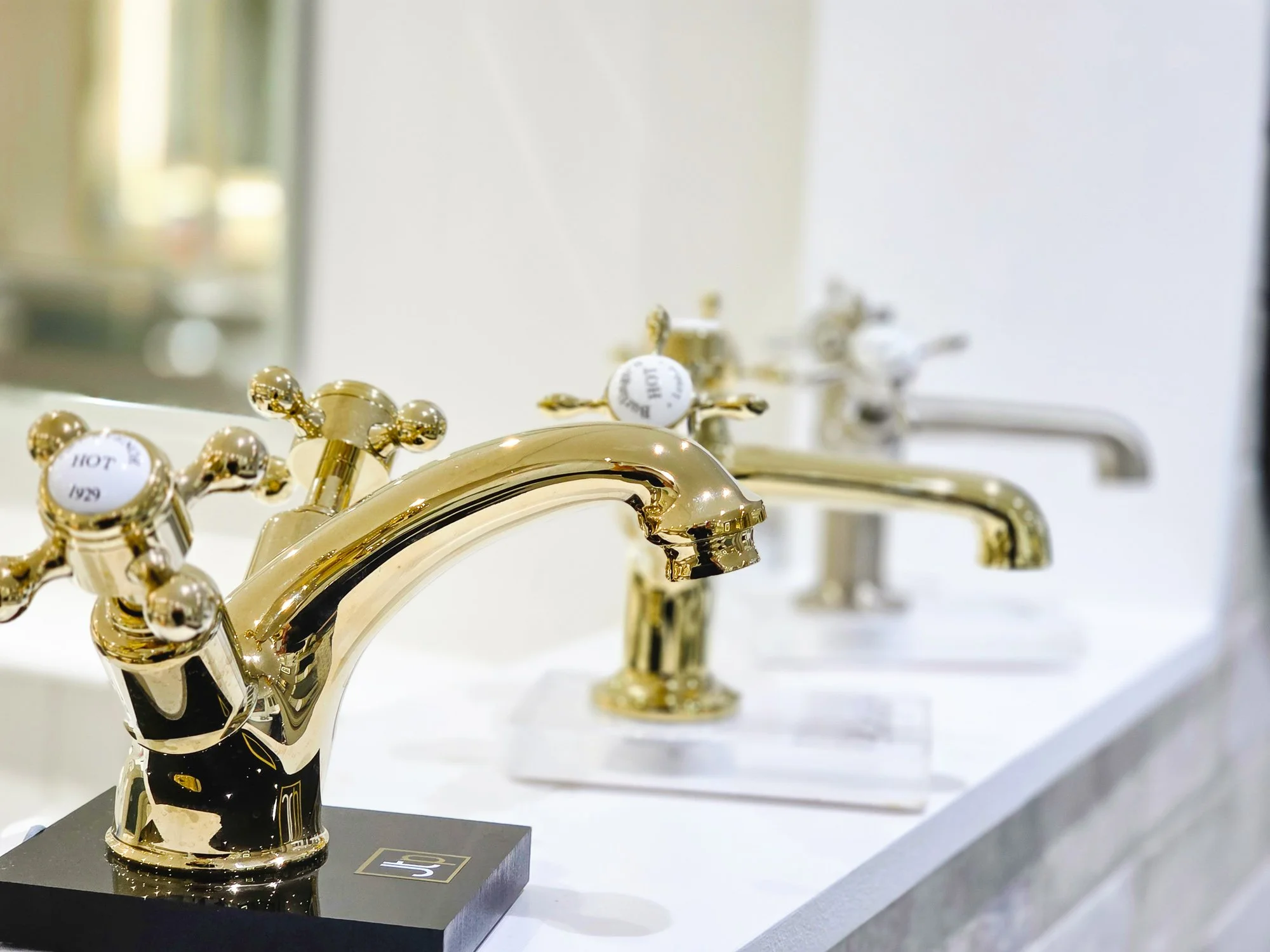 Set of gold and silver decorative faucet handles on display with labels indicating temperature, including 'HOT' and 'COLD'.