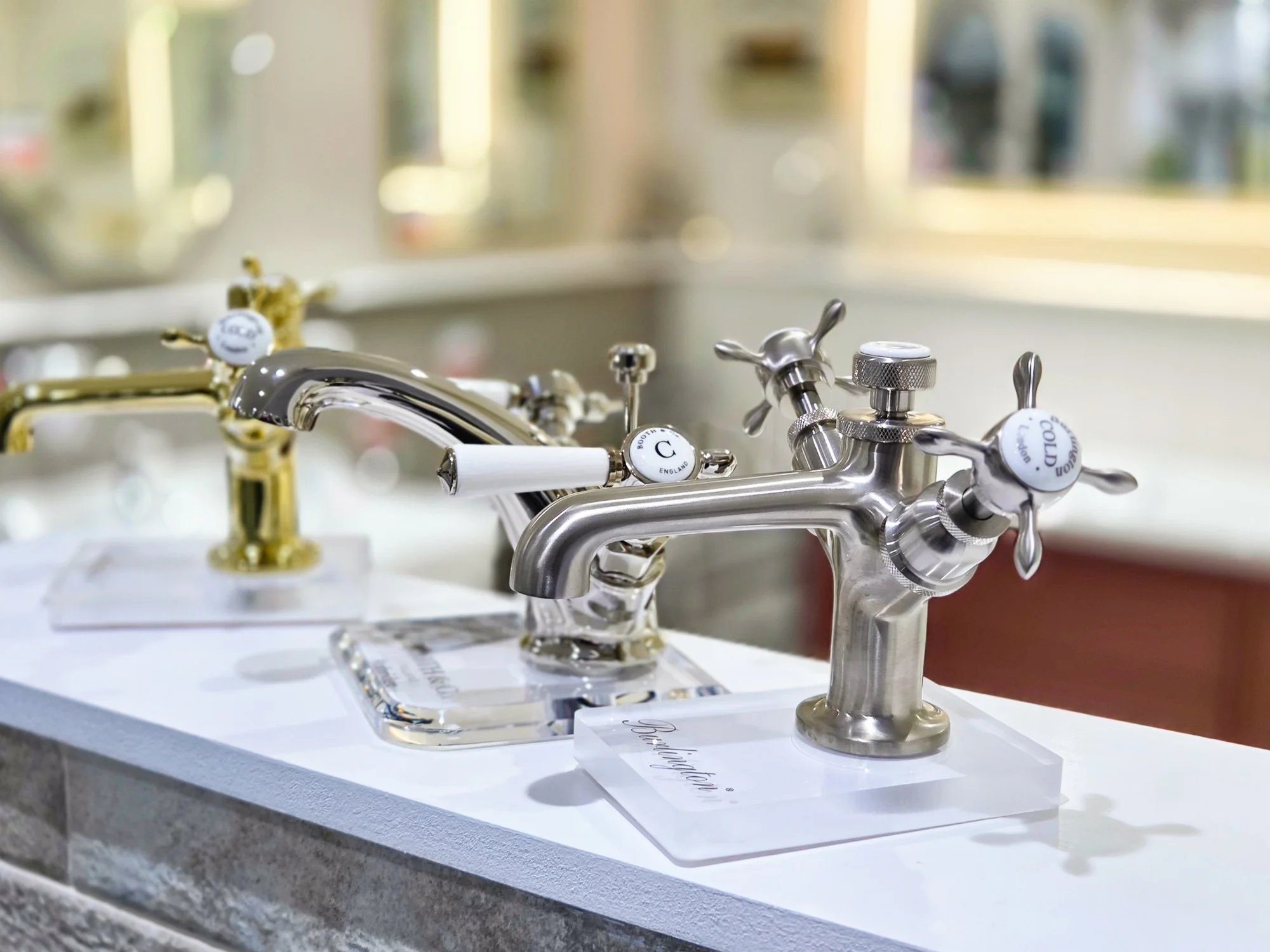 Multiple faucets on display, showcasing different styles and finishes, in a showroom setting.