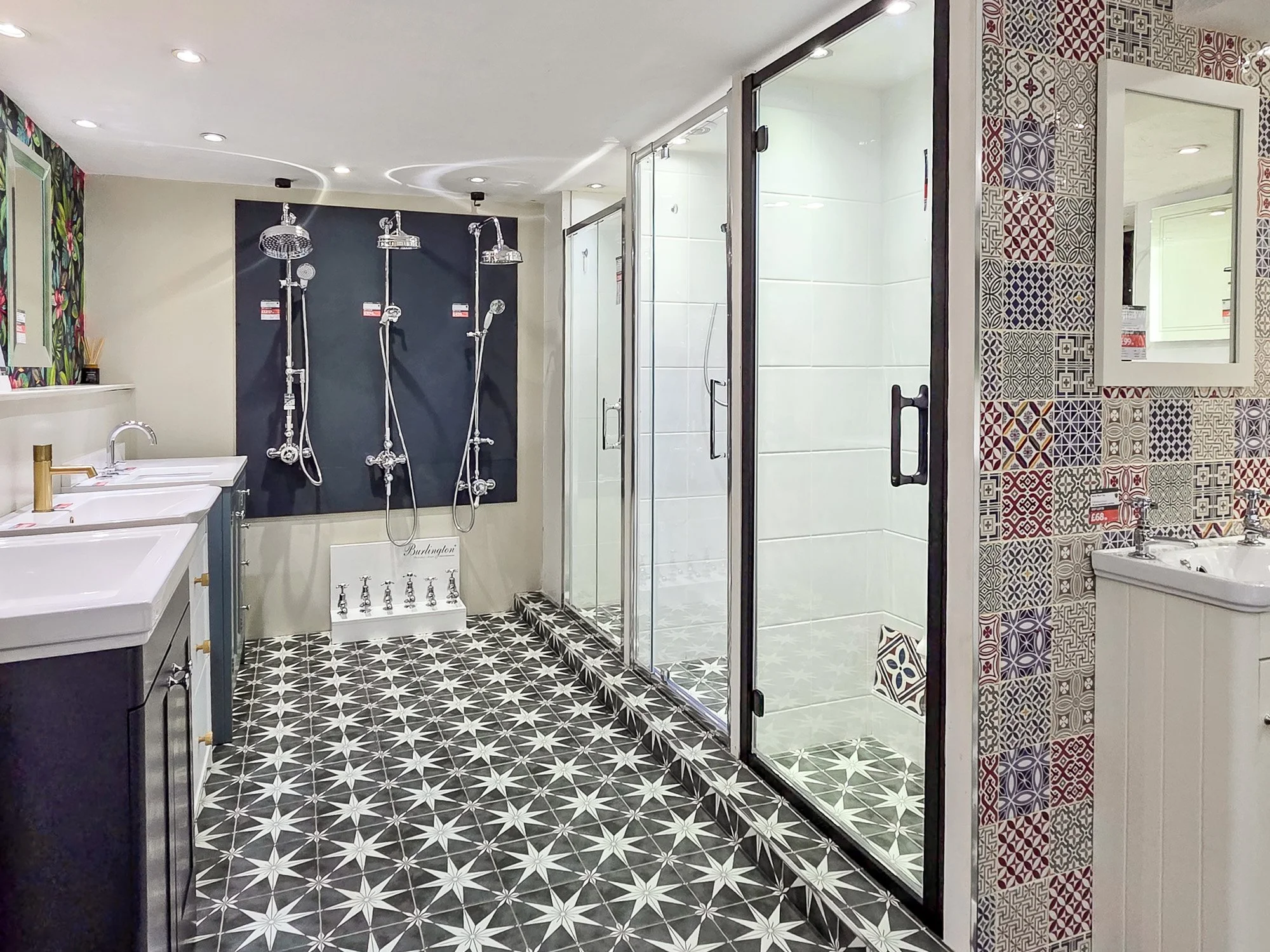 Showroom display of bathroom fixtures including shower heads, sinks, faucets, and colorful tiled walls and flooring.
