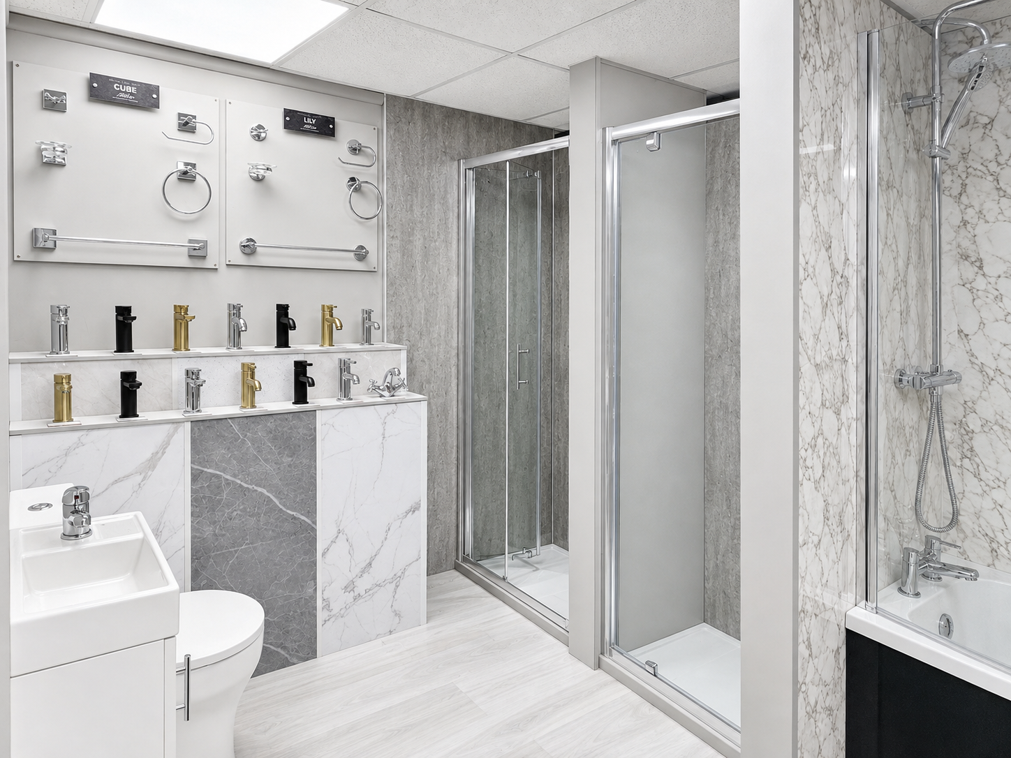 Showroom with various bathroom fixtures, including faucets in black, gold, and silver, towel rings, and bathroom accessories displayed on white panels, along with a shower enclosure, sink, toilet, and bathtub fitted in a modern bathroom setting.