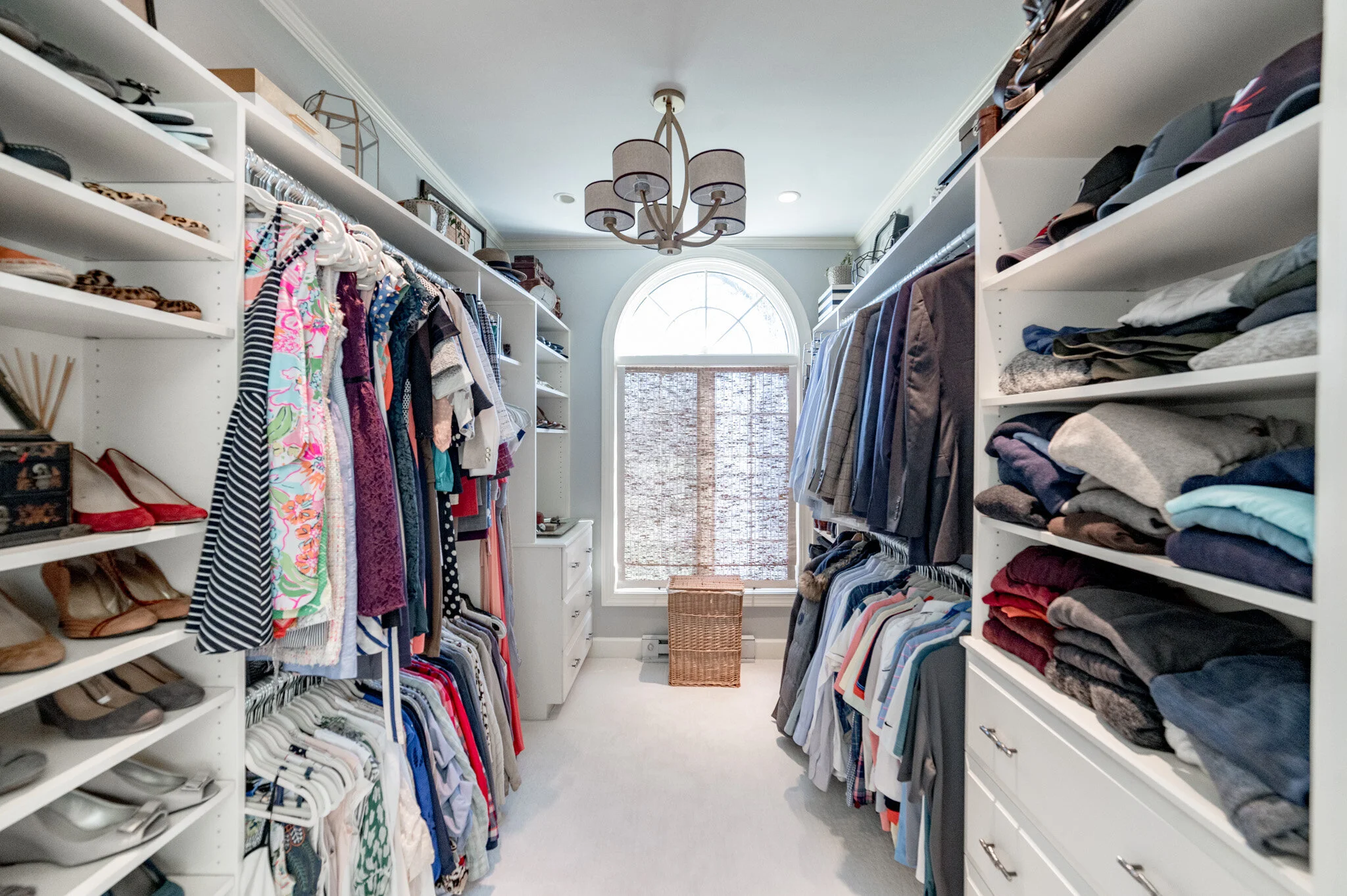 Organized walk-in closet with clothes, shoes, and accessories.