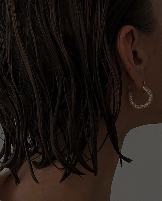 Close-up of a person with wet hair wearing a hoop earring.