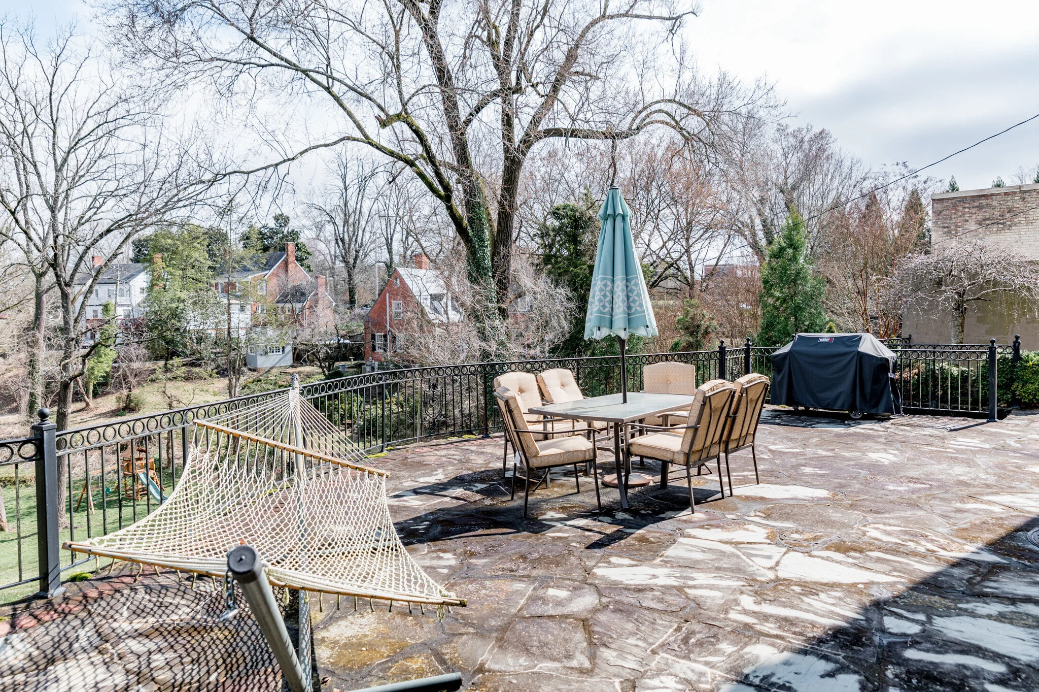 Outdoor patio with a hammock, table, and chairs, umbrella and grill