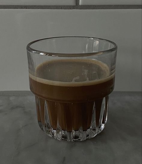 Glass filled with coffee on a marble surface