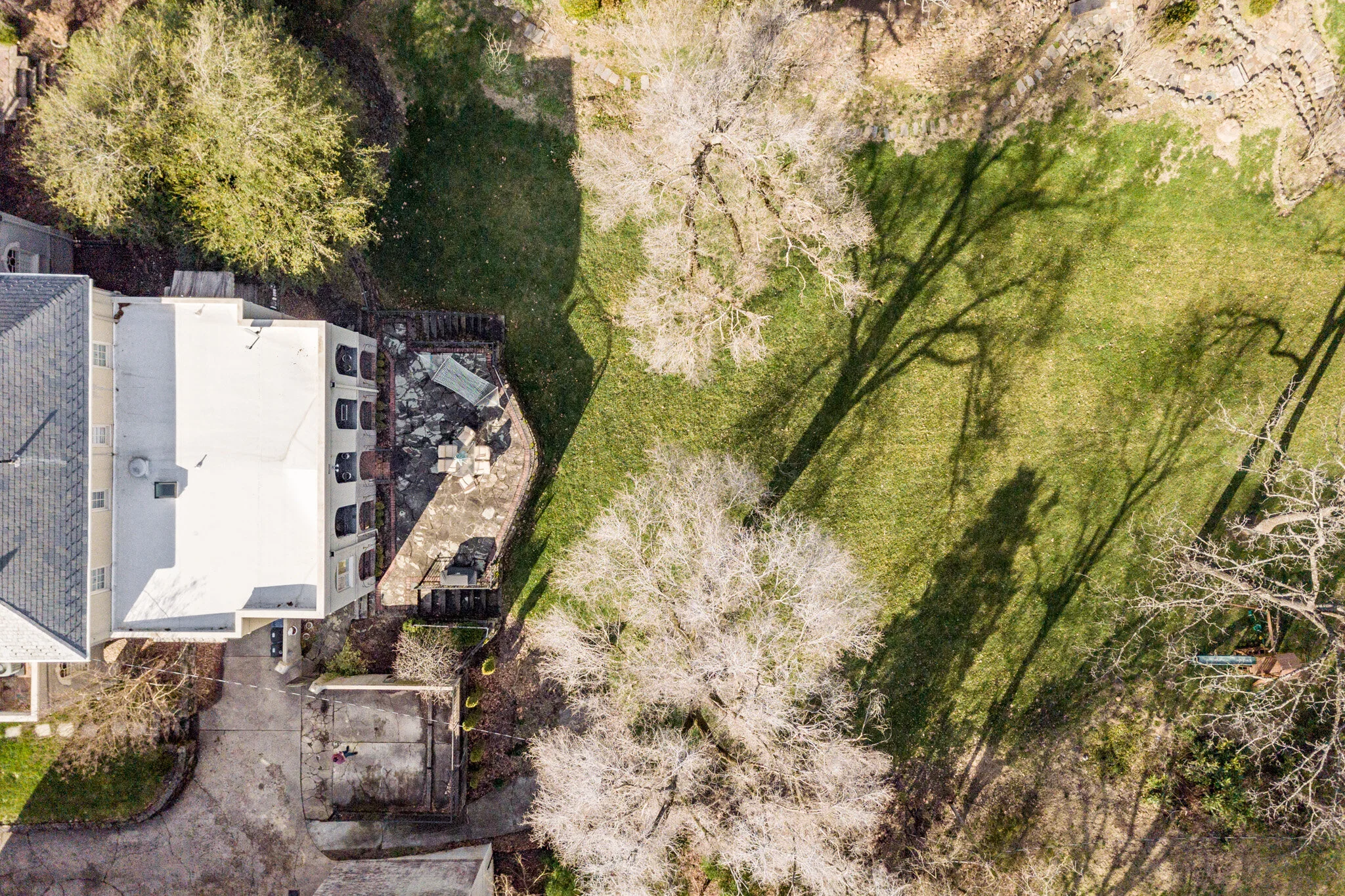 Aerial view of a residential backyard with patio and lawn