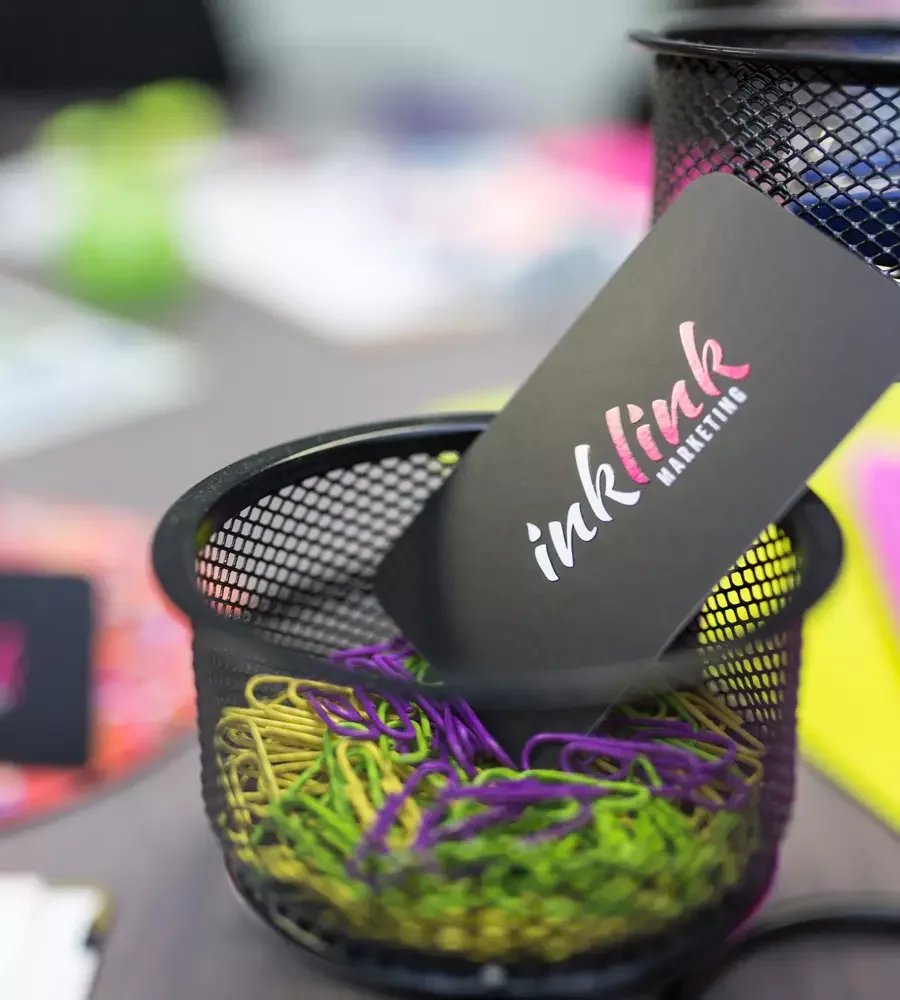 inklink marketing business card in a bowl full of green, purple, and yellow paper clips