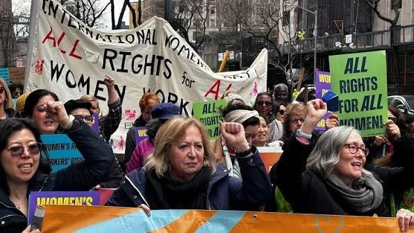 Group of women protesting in a city holding signs advocating for women's rights and equality