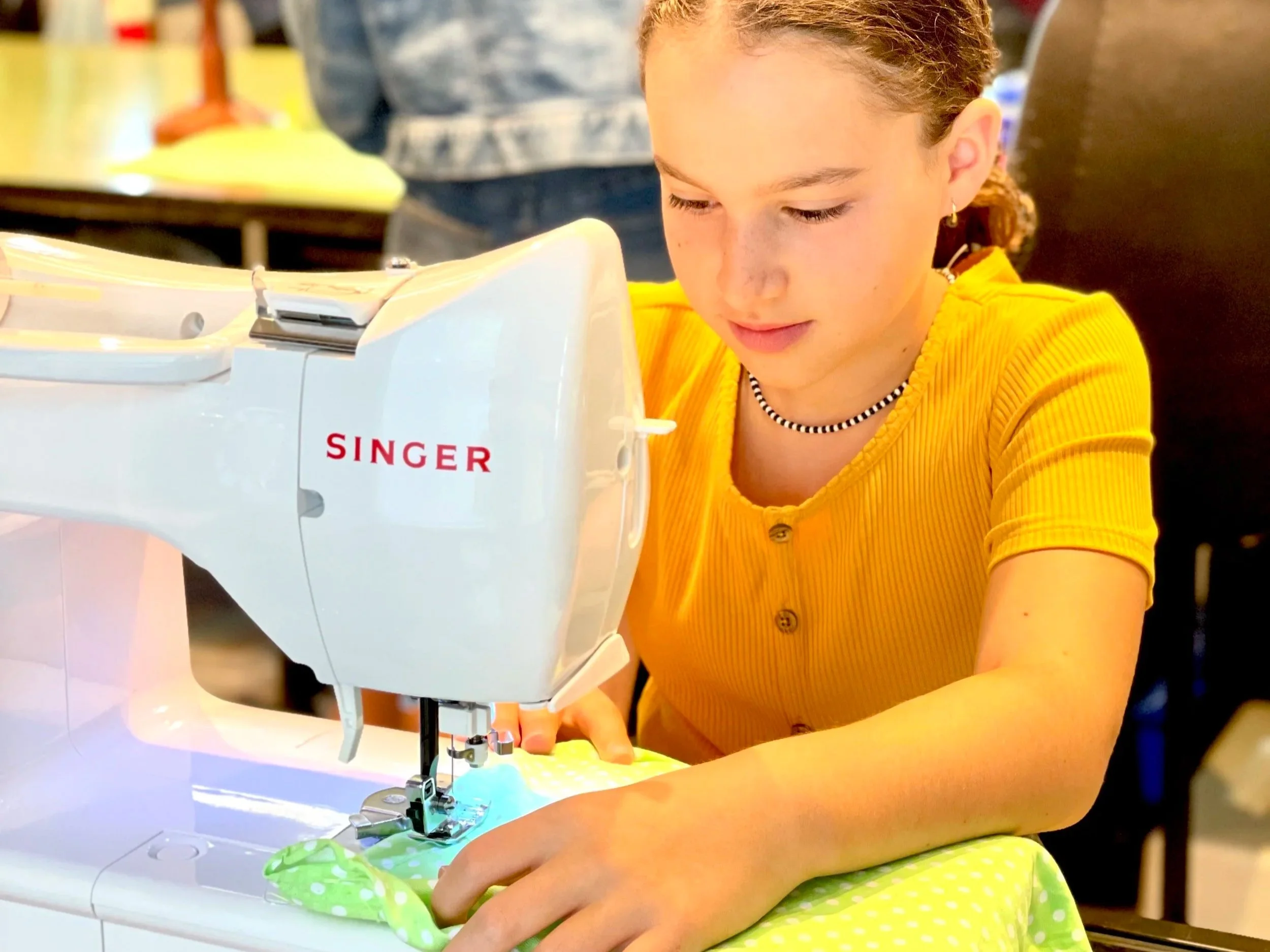 A woman sewing on a white Singer sewing machine.