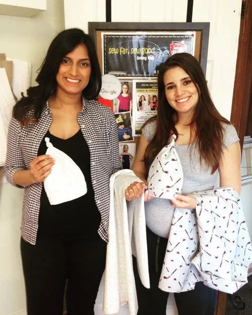 Two adult women showing the sewing projects they completed in sewing classes at Sew Far Sew Good