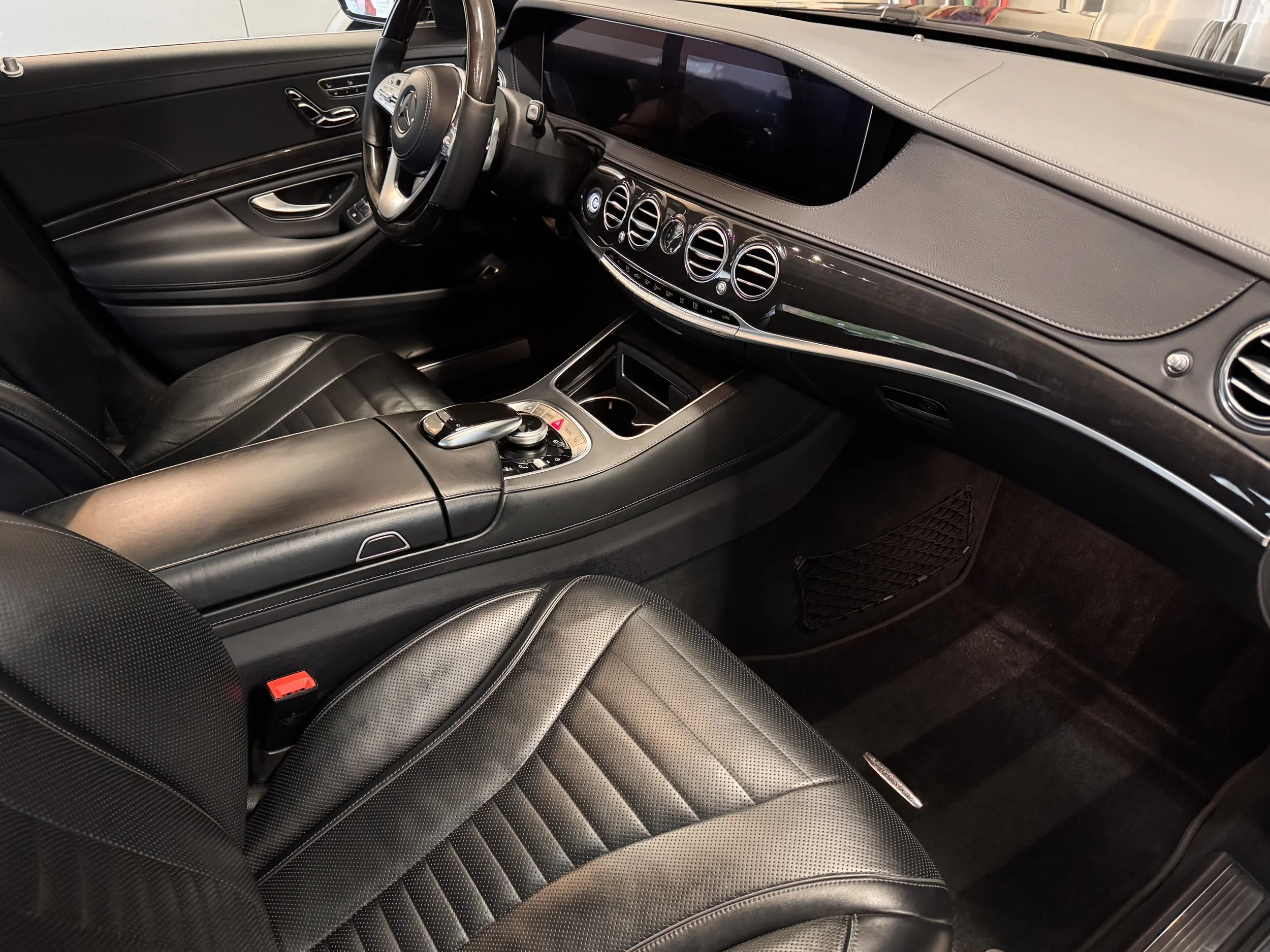 Interior of a modern luxury car with black leather seats, a sleek dashboard with multiple circular air vents, and a center console with a gear shift and control knobs.