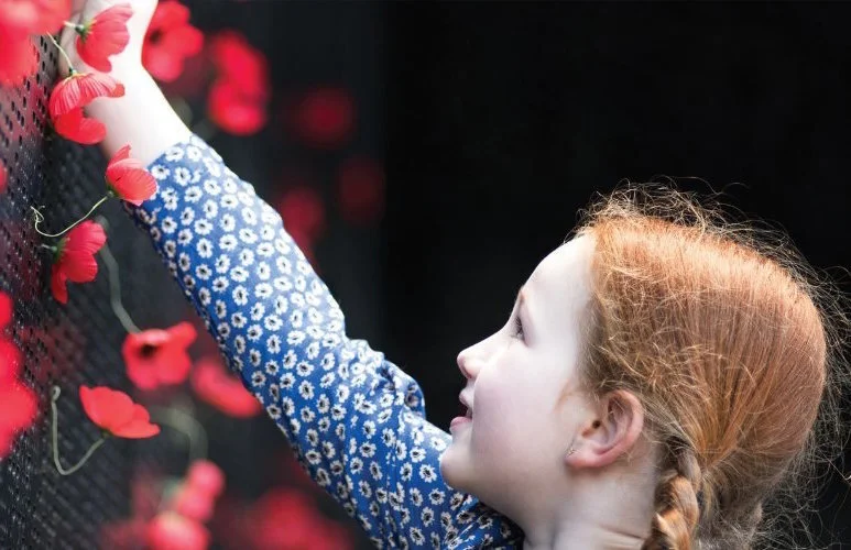 Girl places Poppy on Wall of Remembrance
