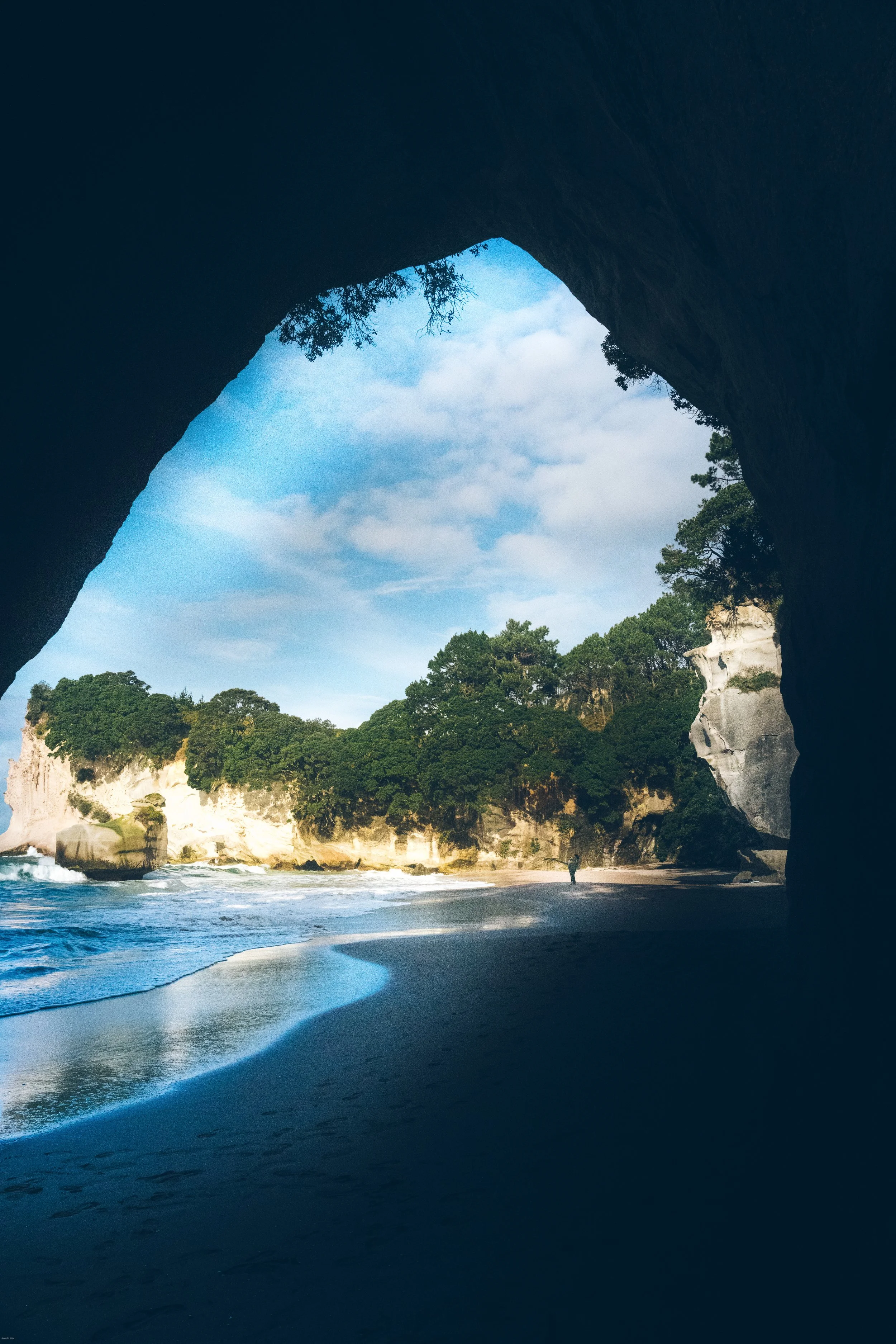 View of a beach seen from inside a large rock formation with a natural arch at Cathedral Cove, Coromandel Peninsula, North Island, New Zealand.