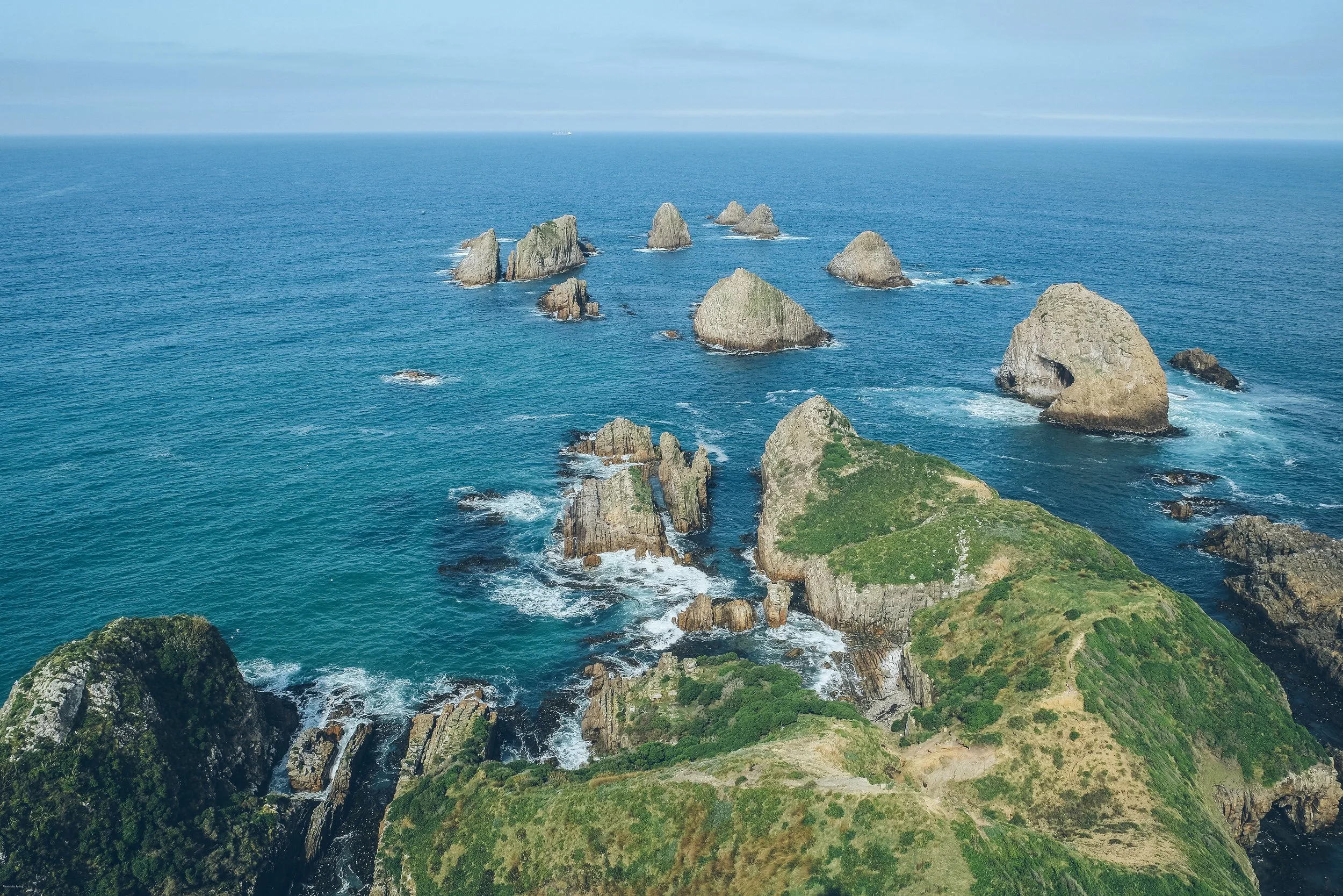 The dramatic sea stacks of Nugget Point on the rugged Catlins coast in Otago, South Island, New Zealand, surrounded by the blue waters of the Pacific Ocean.