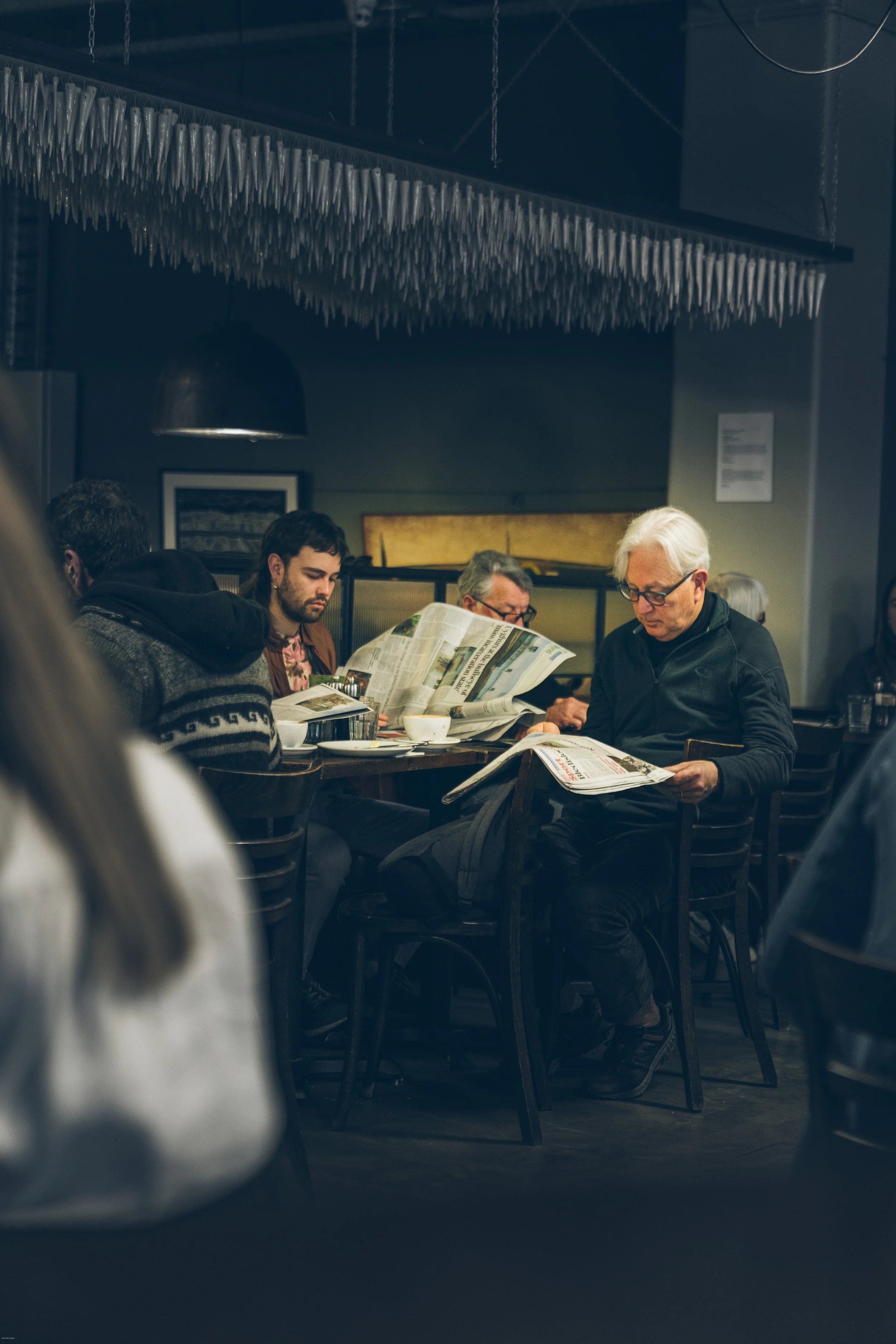 Locals reading newspapers over coffee inside Café L’Affare in Wellington, New Zealand, reflecting the capital city’s vibrant café and coffee culture.