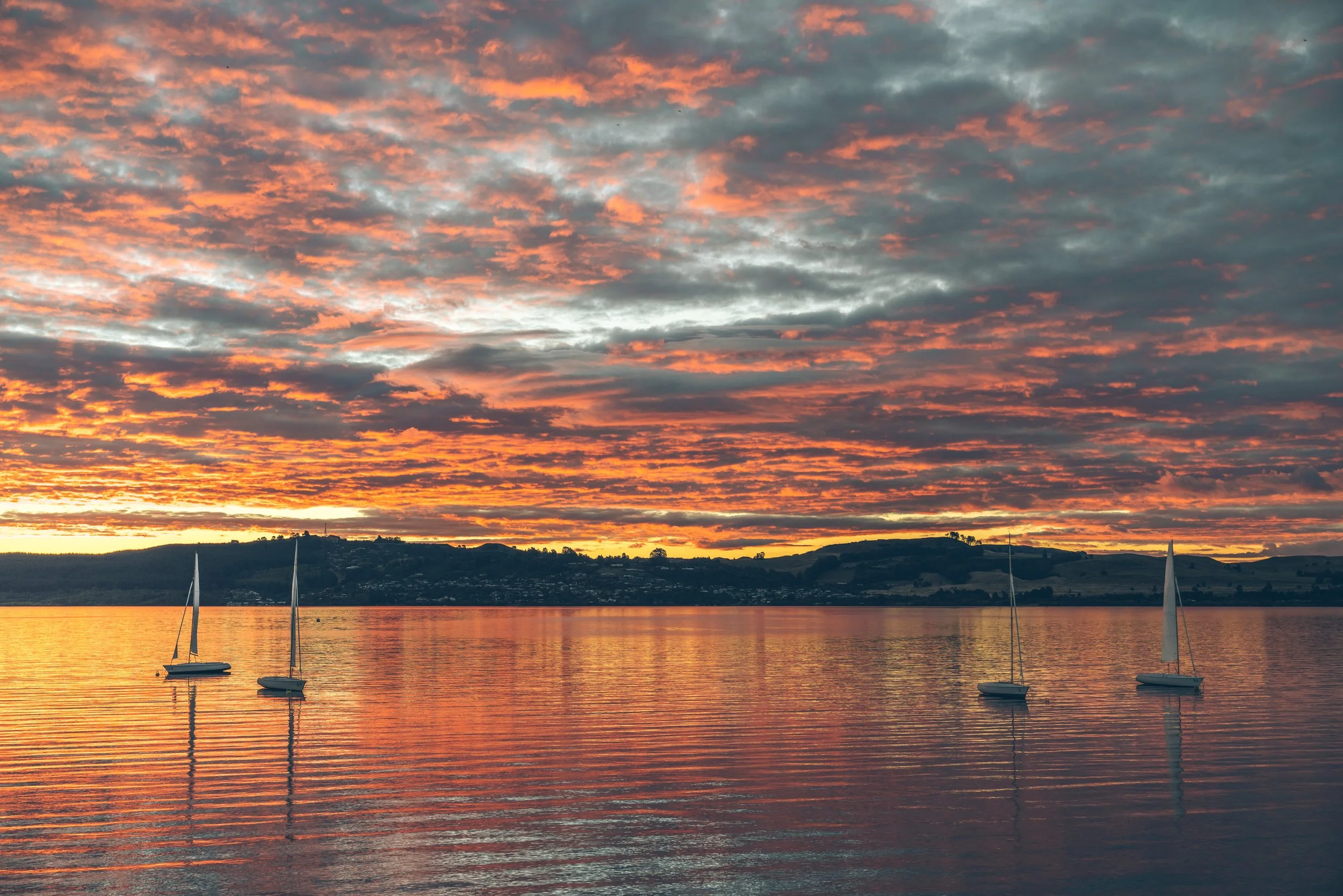 Two Mile Bay Beach Club at sunset overlooking Lake Taupō, where sailboats drift across New Zealand's largest lake in Waikato on the North Island.