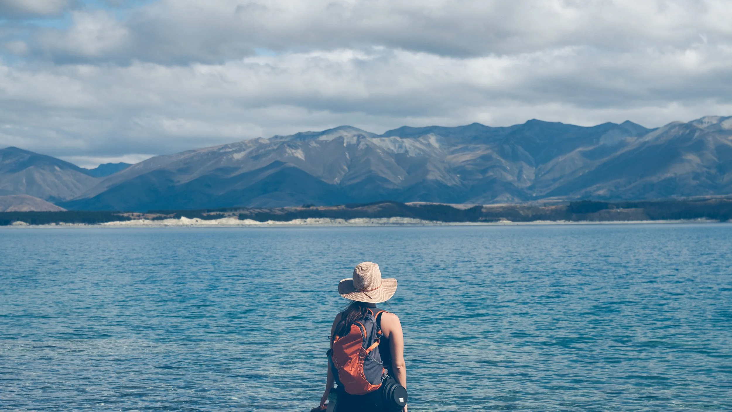 A traveler overlooking the turquoise waters of Lake Pukaki with Aoraki Mount Cook National Park in the background on New Zealand's South Island.