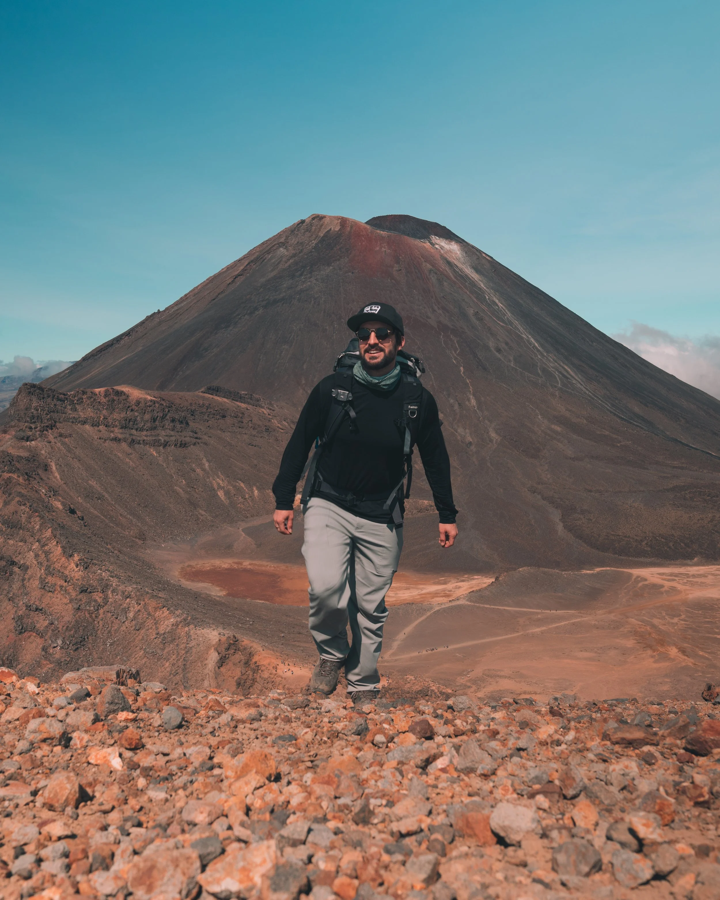 Alexander Ayling hiking the Tongariro Alpine Crossing with the volcanic peak of Mount Ngauruhoe in the background, North Island, New Zealand.