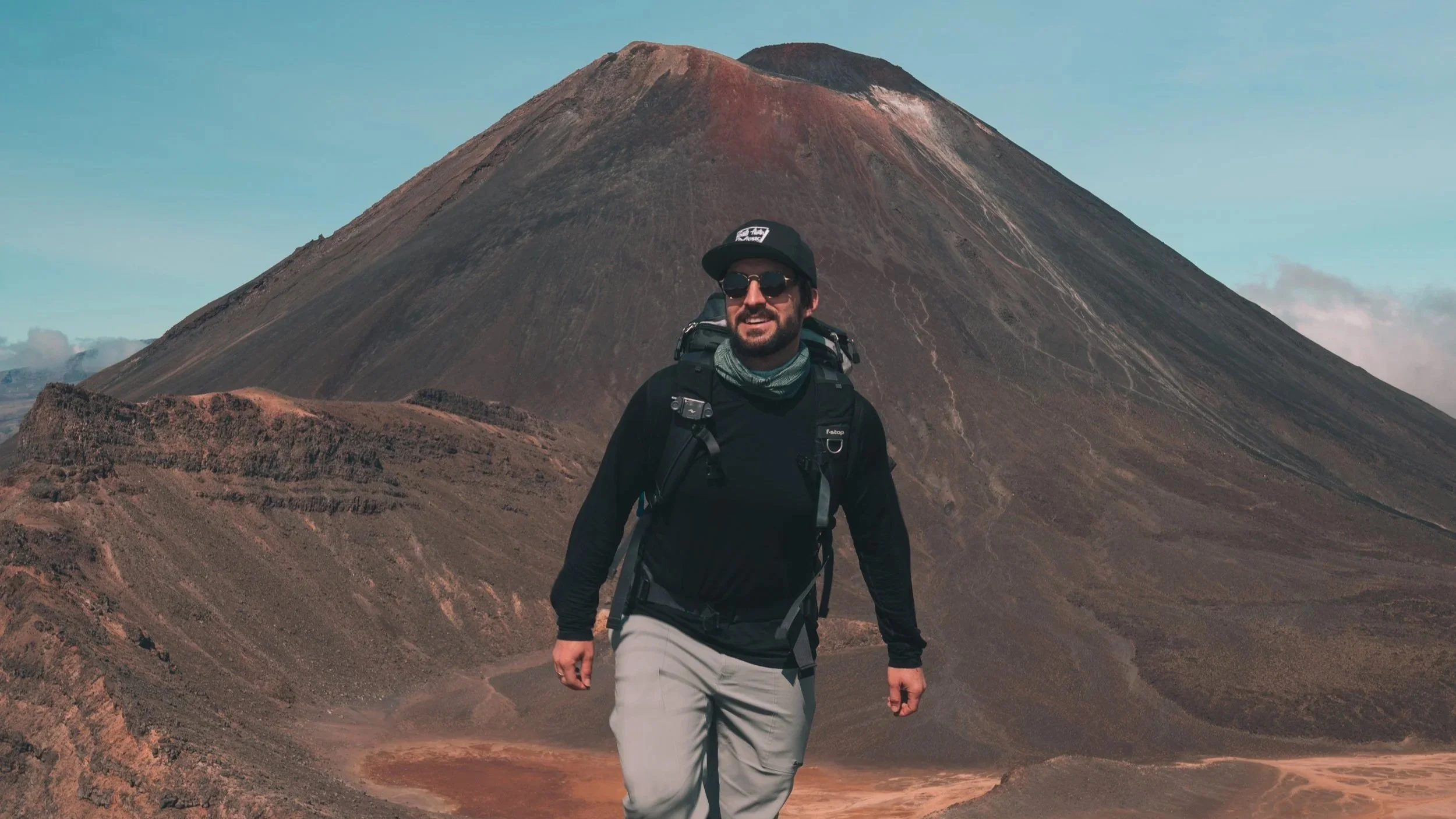 Alexander Ayling hiking the Tongariro Alpine Crossing with Mount Ngauruhoe rising behind him in Tongariro National Park, one of New Zealand's most iconic day hikes.