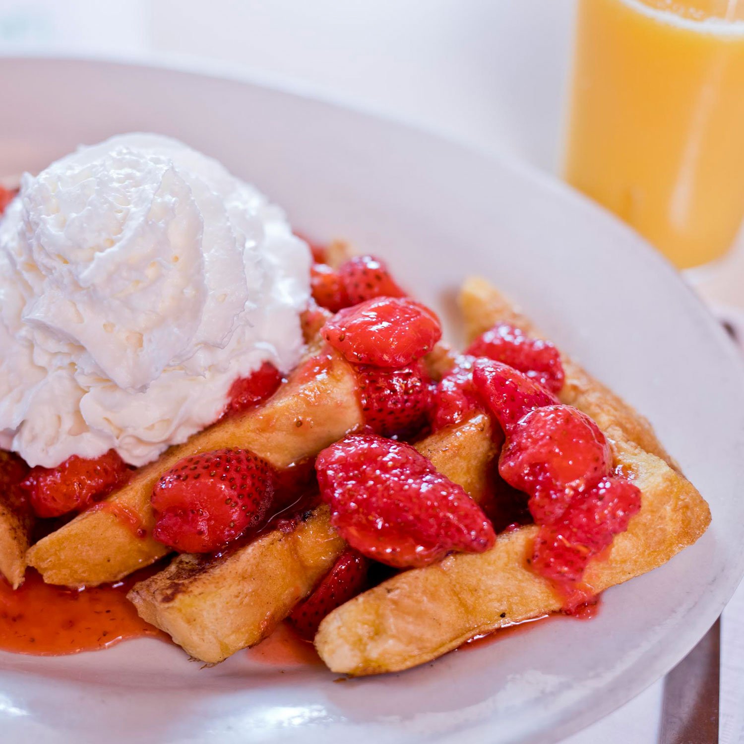  several slices of belgian waffles drizzled with sweet strawberries and whipped cream  