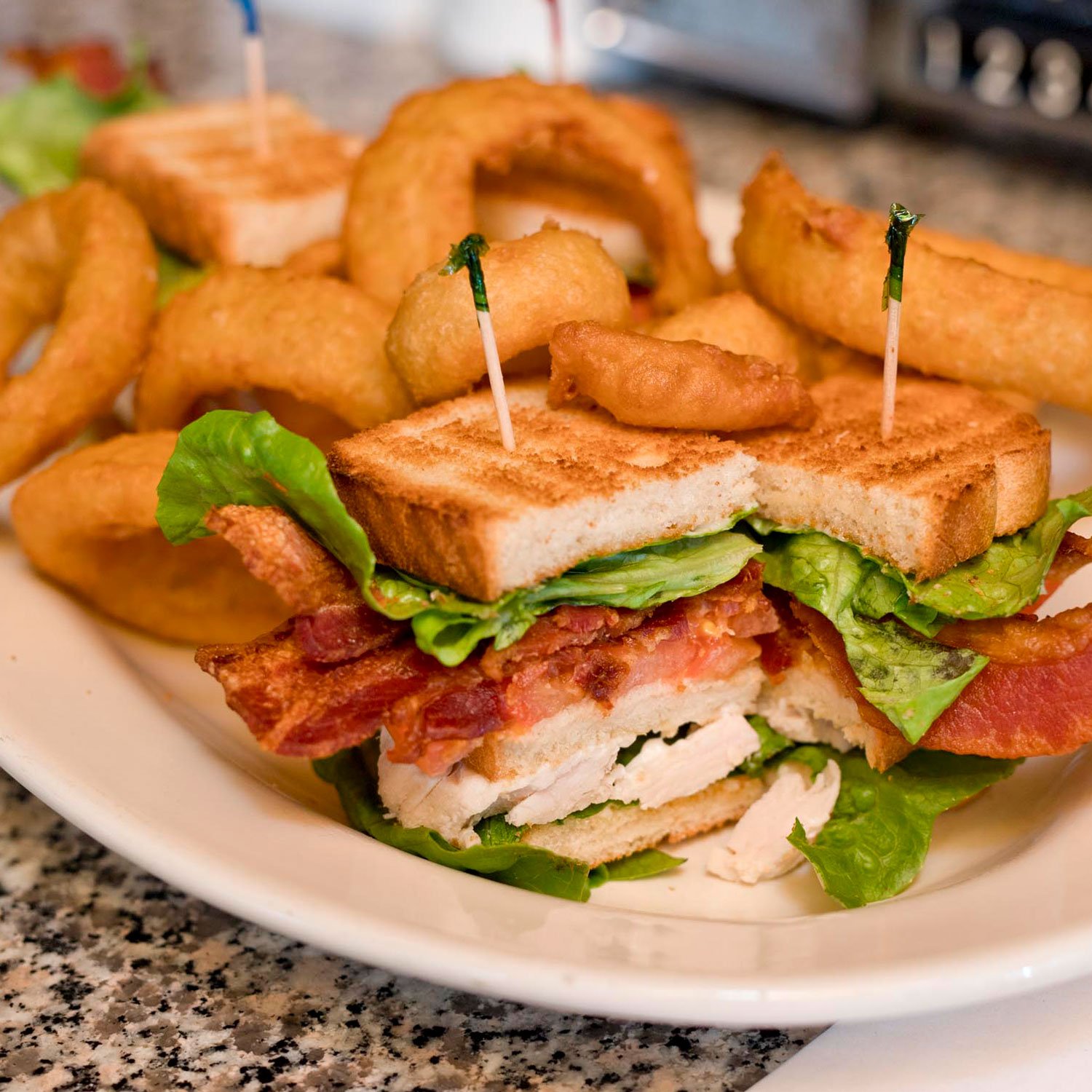  traditional club sandwich with fresh white meat turkey, crisp bacon, lettuce, tomato and mayo layered with toast and a side of crispy onion rings 
