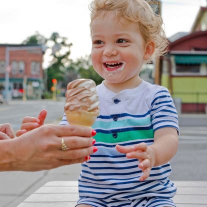  little toddler smiles wide being handed a soft serve twist cone 