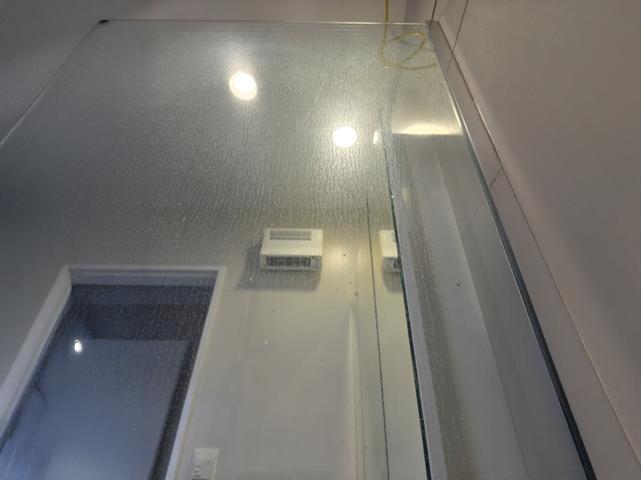 Upward angle photo from inside shower showing glass staining clearly