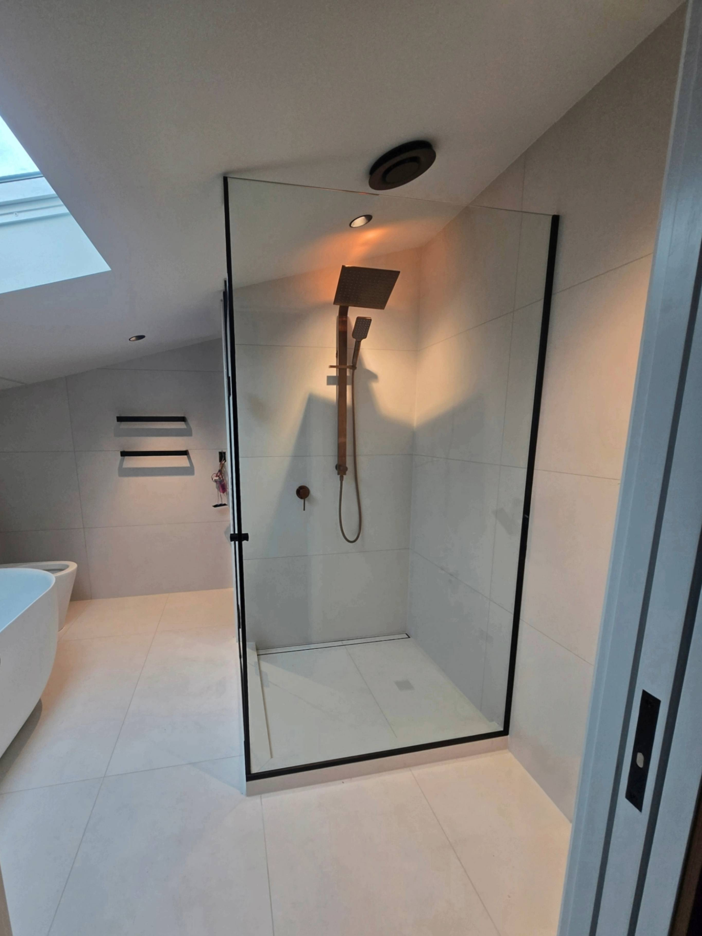 Corner shower enclosure with black frame and hinged door in a modern tiled bathroom