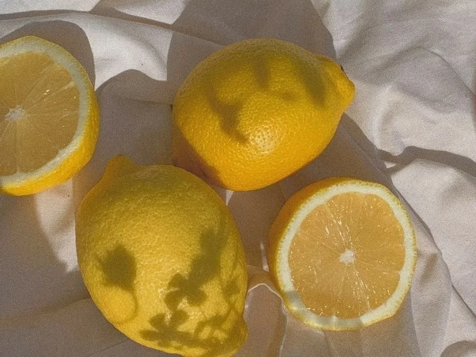 Two whole lemons and two lemon halves on a white cloth.
