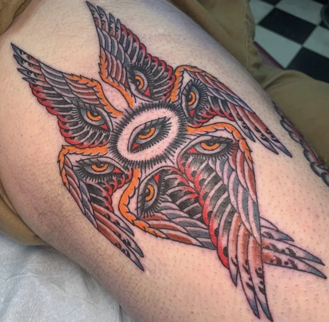 Colorful tattoo of a supernatural creature with multiple eyes, wings, and an intricate design.